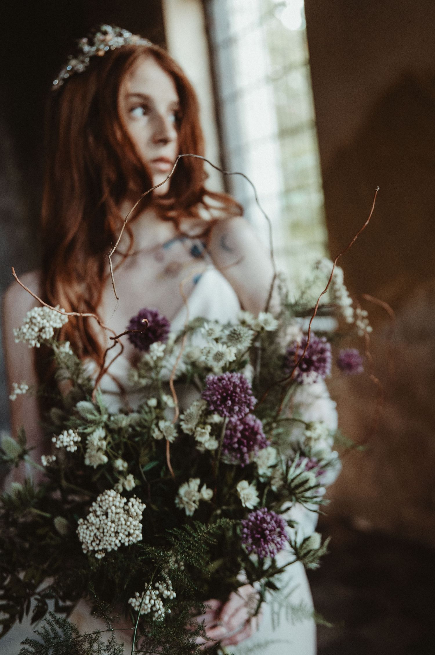 Artistic wedding photo with soft focus flowers and natural window light.
