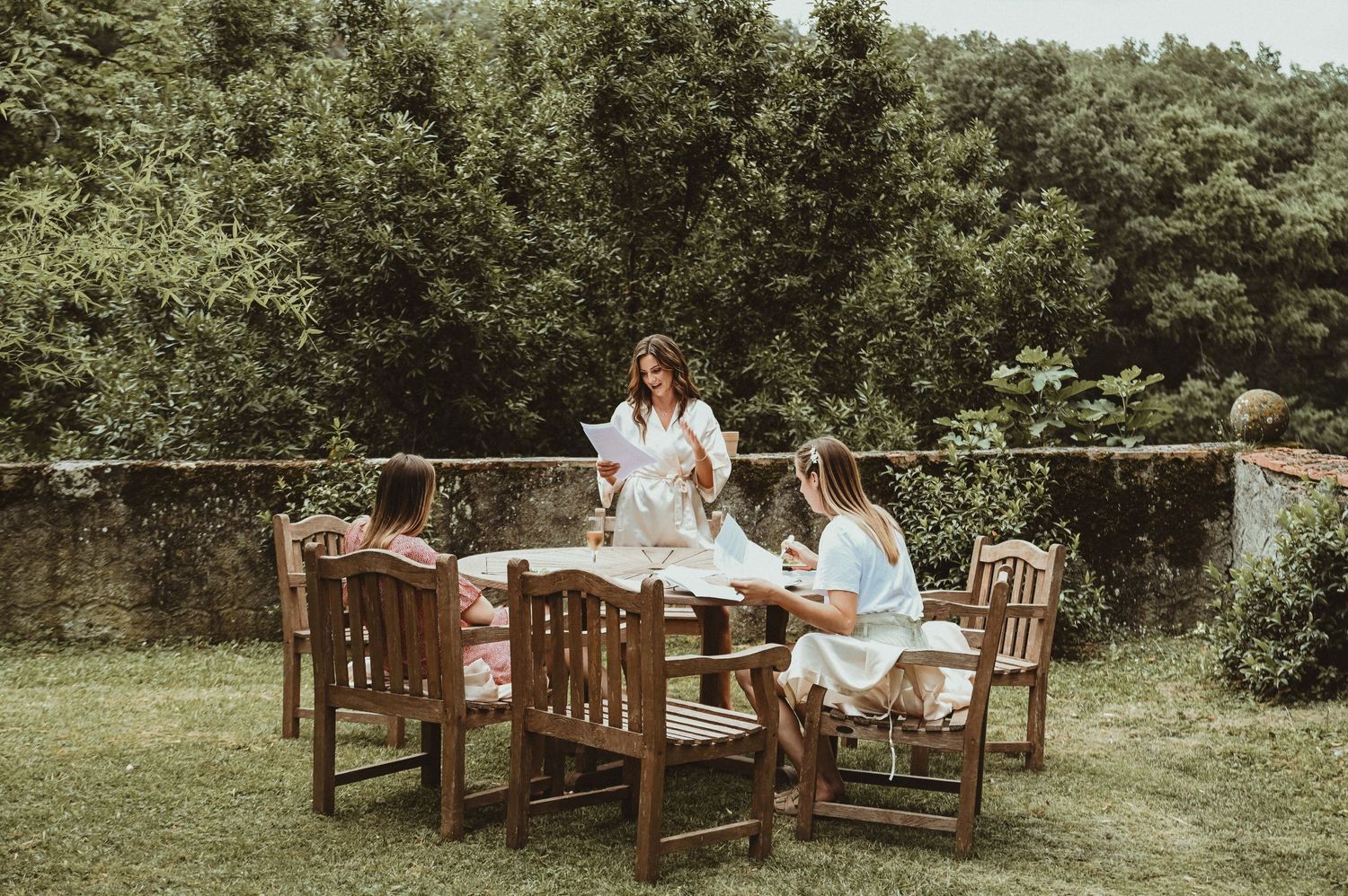 Outdoor garden lunch setting with wooden furniture and guests enjoying a meal.