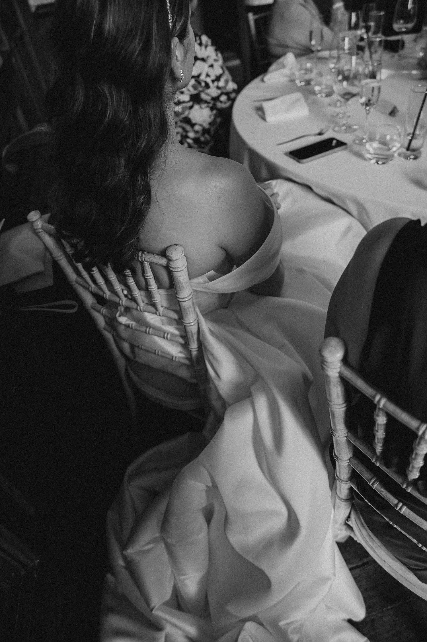 Black and white photo of elegant wedding reception with guests seated at dining tables.
