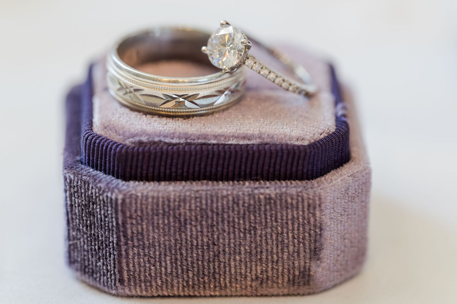 Diamond engagement ring and wedding band displayed in a purple velvet ring box.