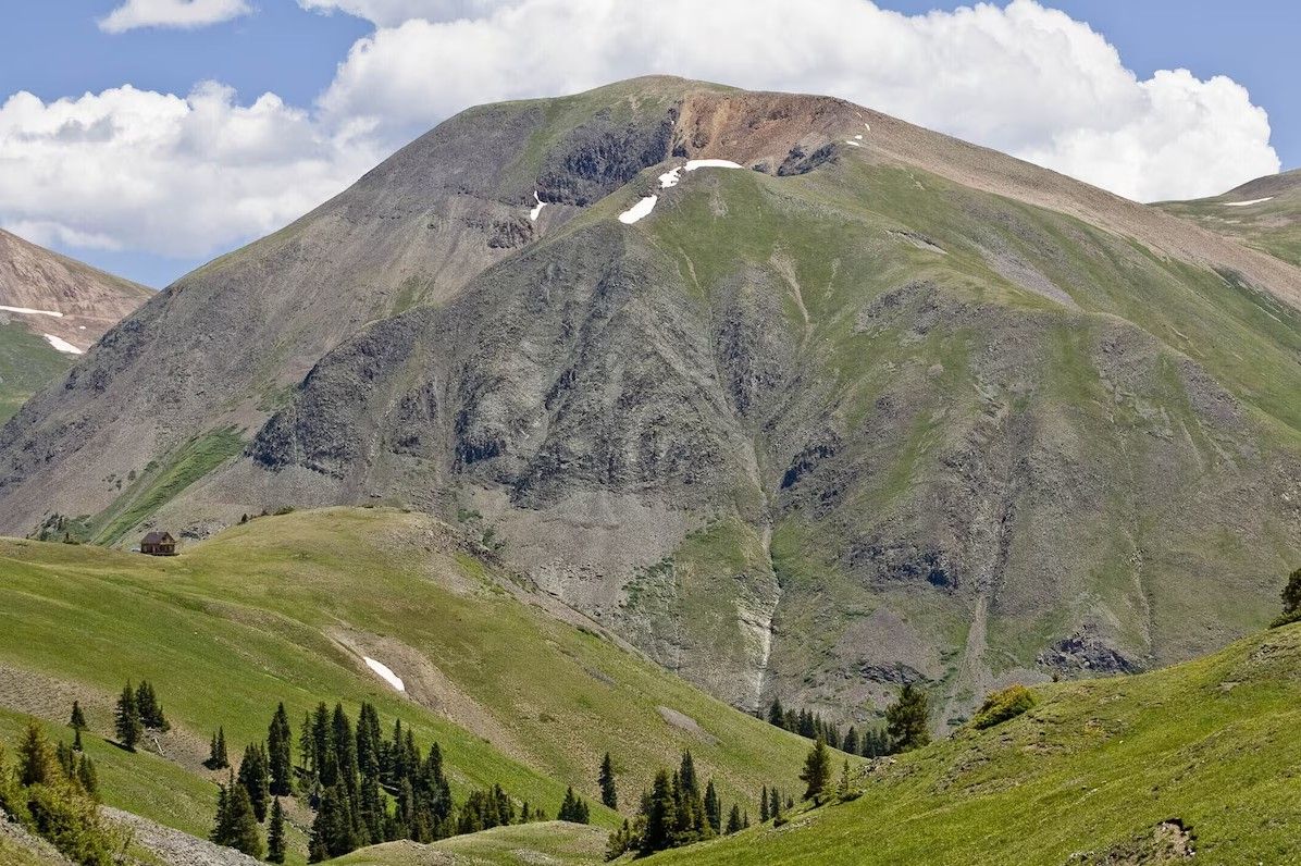 Panoramic view of rugged mountain peaks and green slopes in the San Juan mountains under blue summer skies near Silverton.