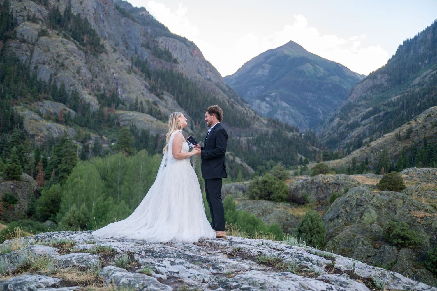 Bride and groom exchange vows on a rocky mountain overlook surrounded by stunning Colorado peaks.