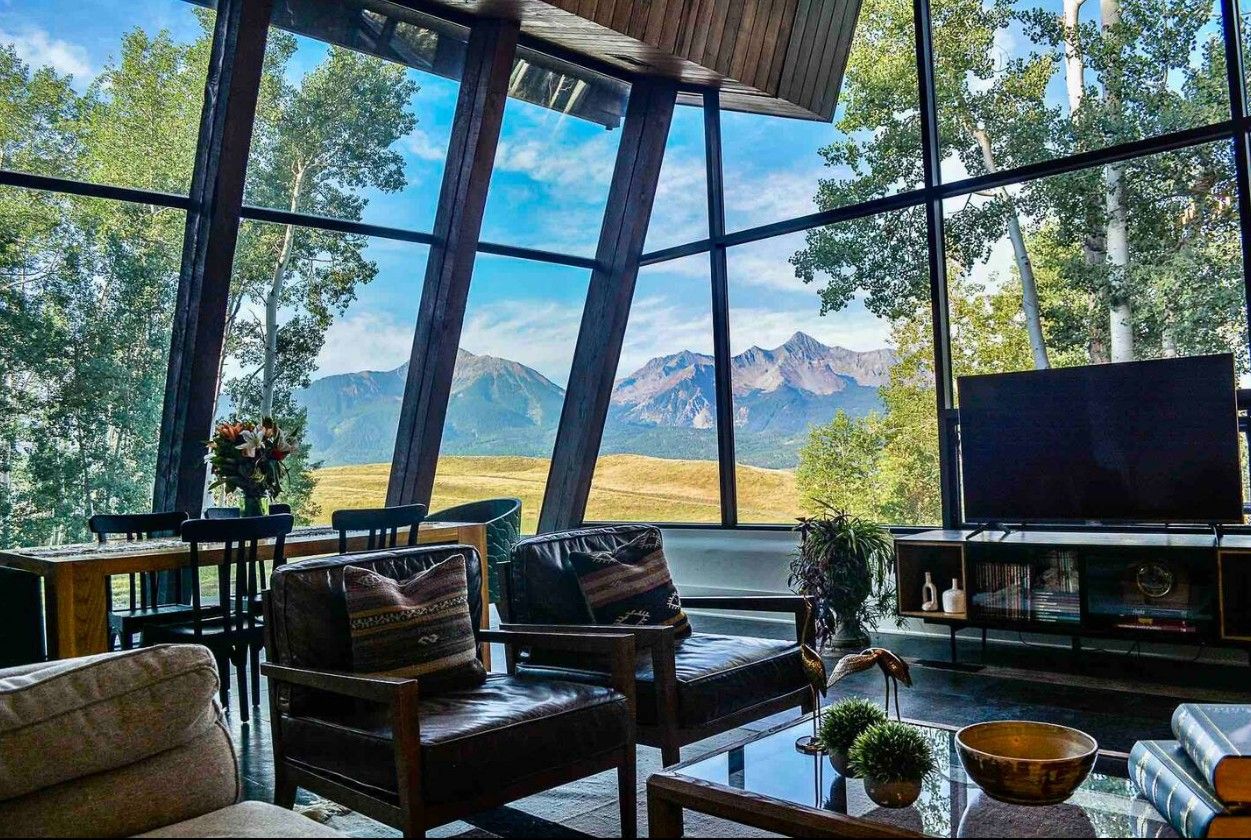 A view out the floor to ceiling windows of an Airbnb near Telluride with the iconic peak of Mt. Wilson in the distance.