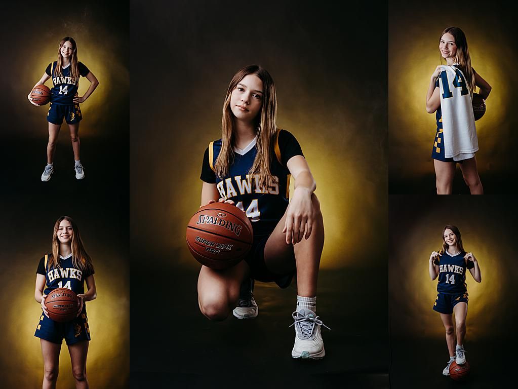 Basketball player in navy blue uniform holds ball while posing for dramatic sports portrait against dark background.