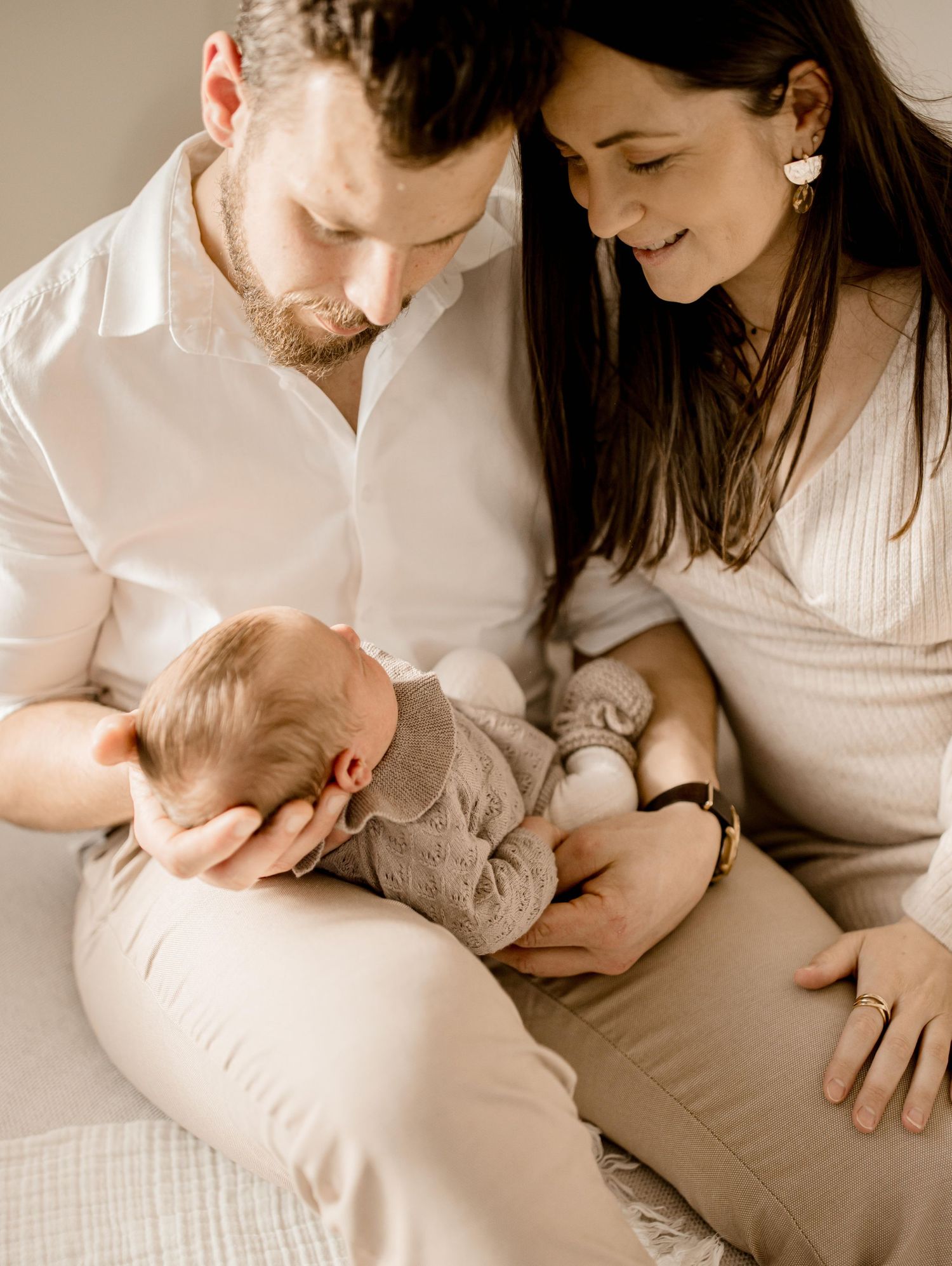Family moment with newborn baby in soft neutral tones.