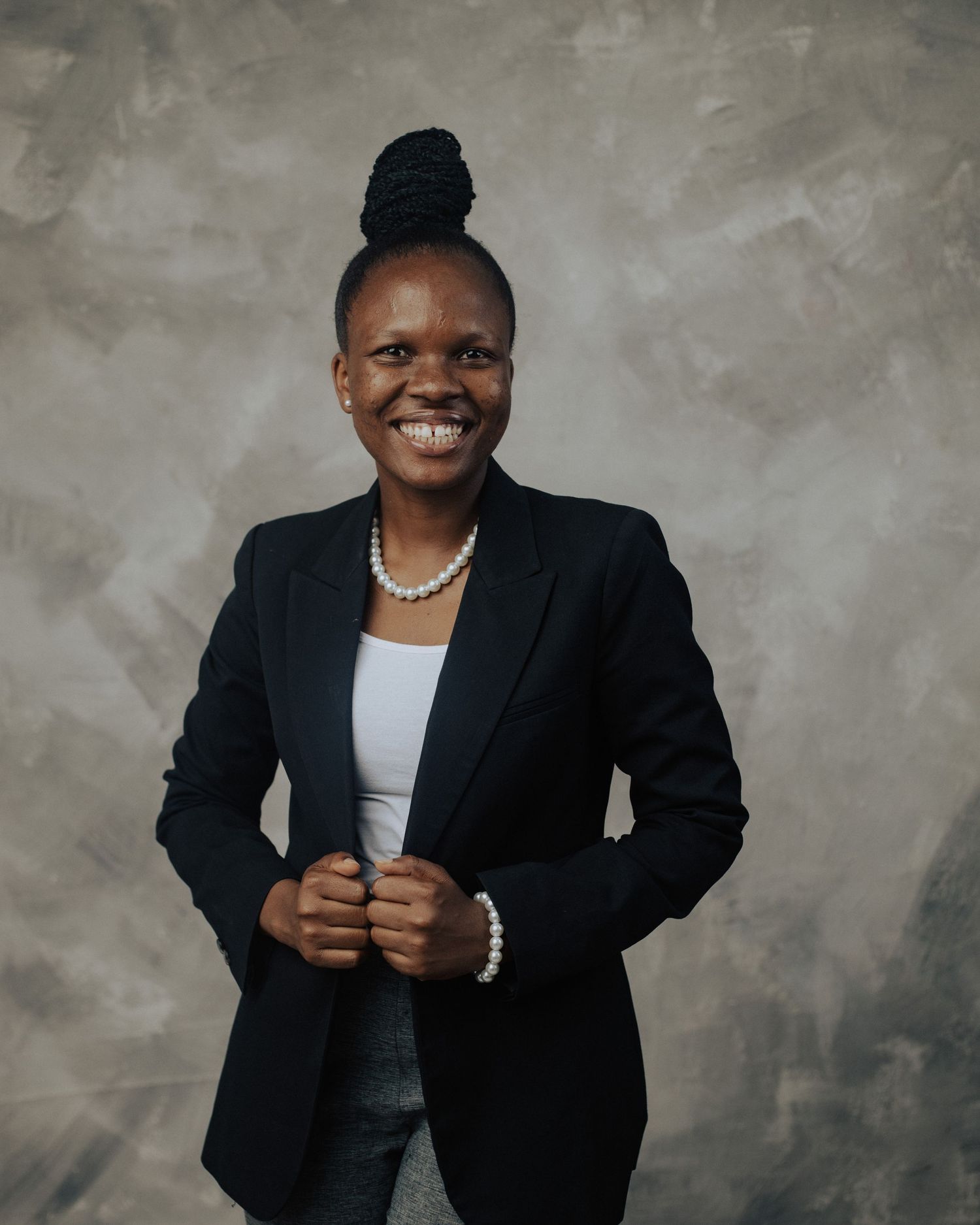 Professional studio portrait series showing a person in a black blazer and white shirt against a textured gray background.