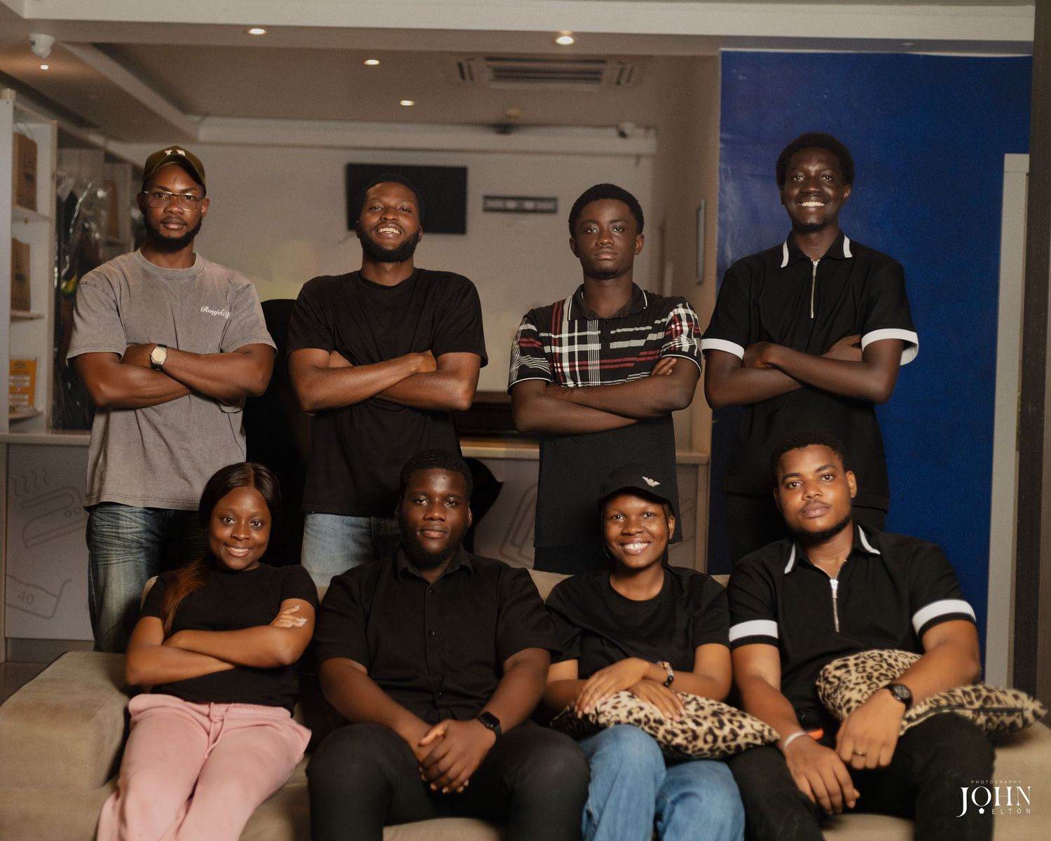 A group poses together in a studio setting with blue walls and lighting visible in the background.