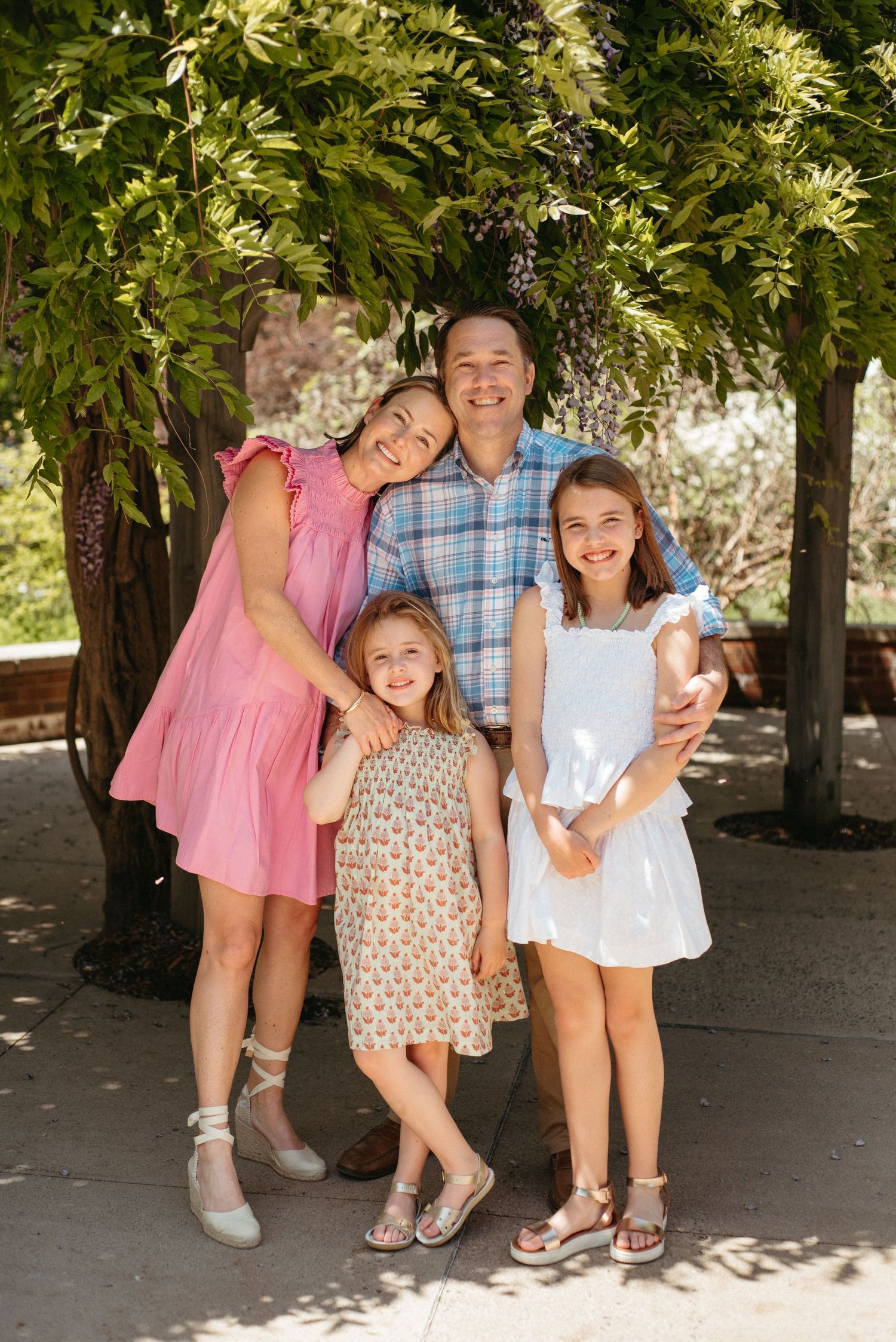 Family portrait series showing joyful expressions and embraces under tree canopy.