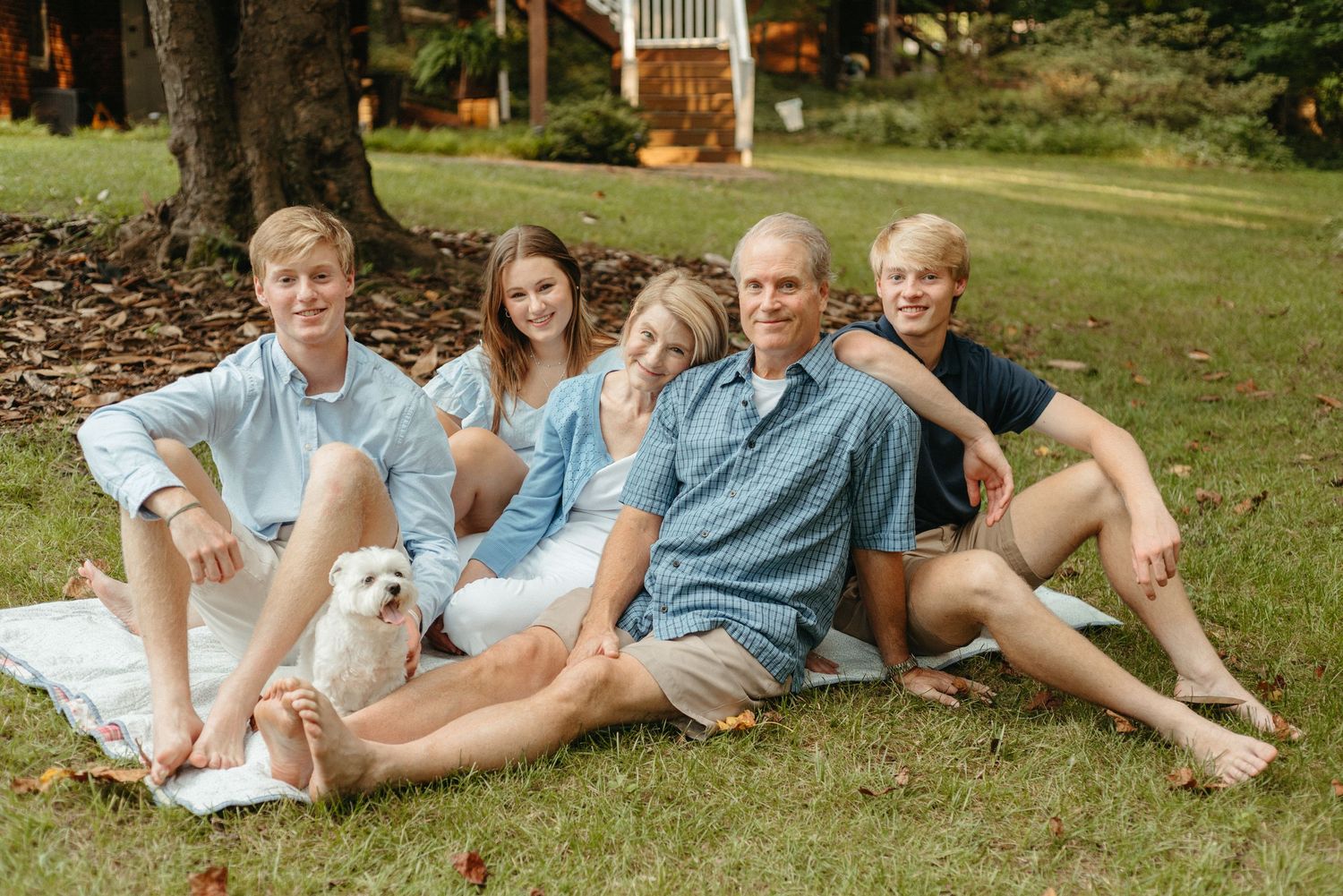 Casual family portrait with everyone lounging on grass together.