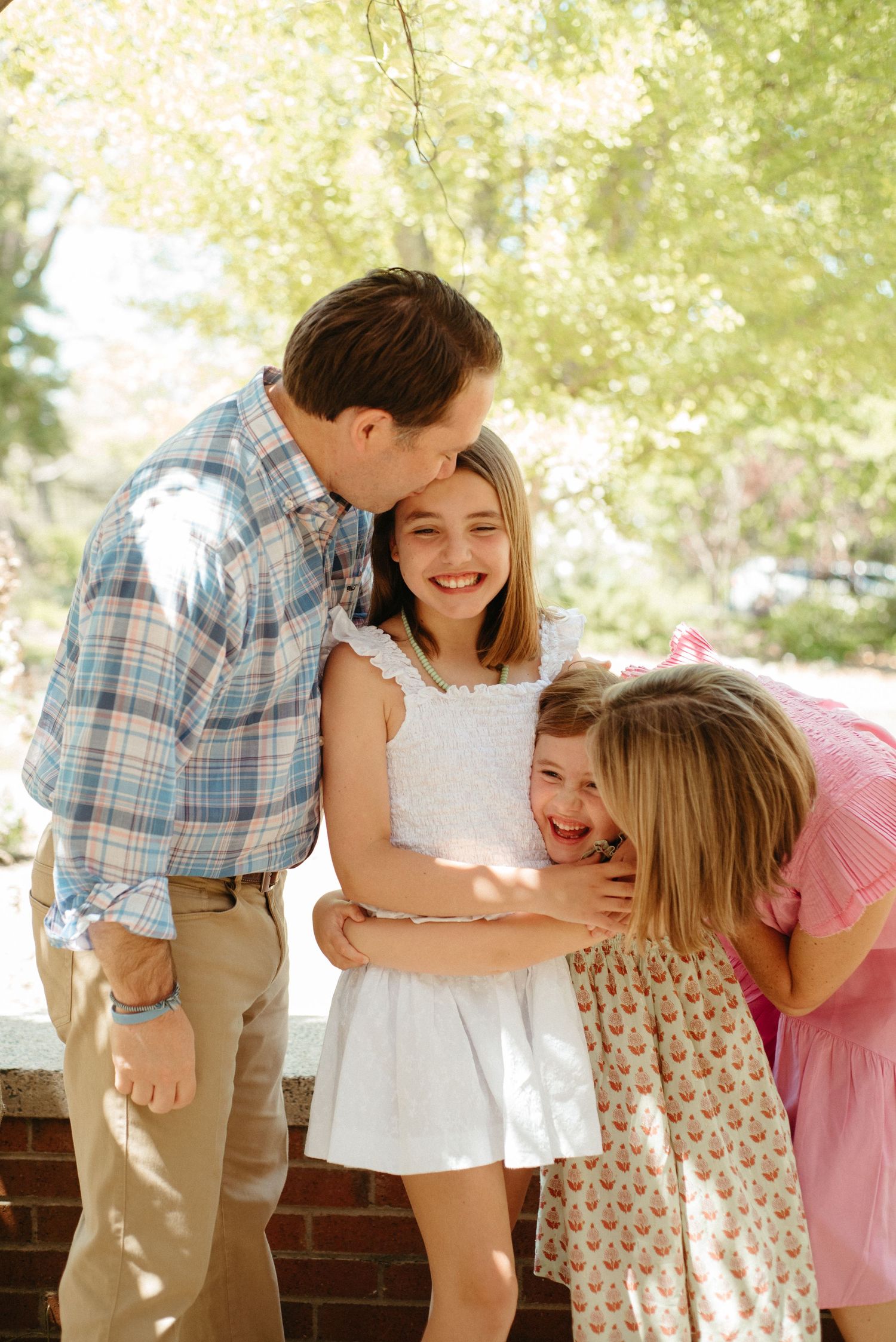 Sweet family interaction captured in a series of candid moments under dappled sunlight.