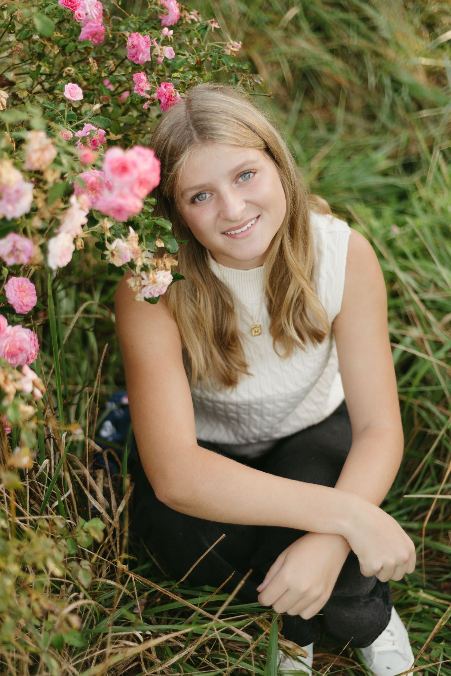 Pink roses frame a casual outdoor portrait among lush greenery.