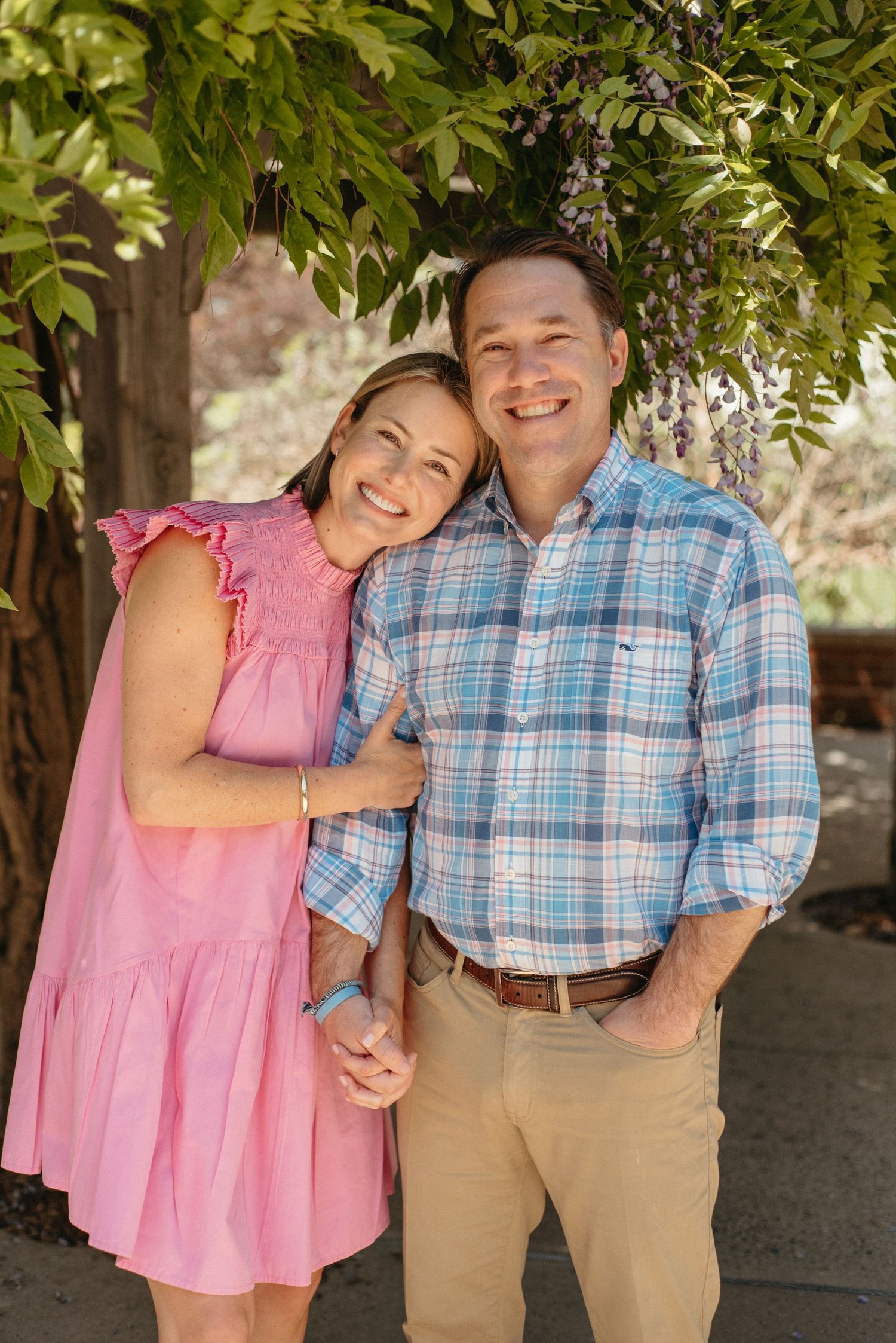 Candid outdoor family photos showing playful moments under green trees.