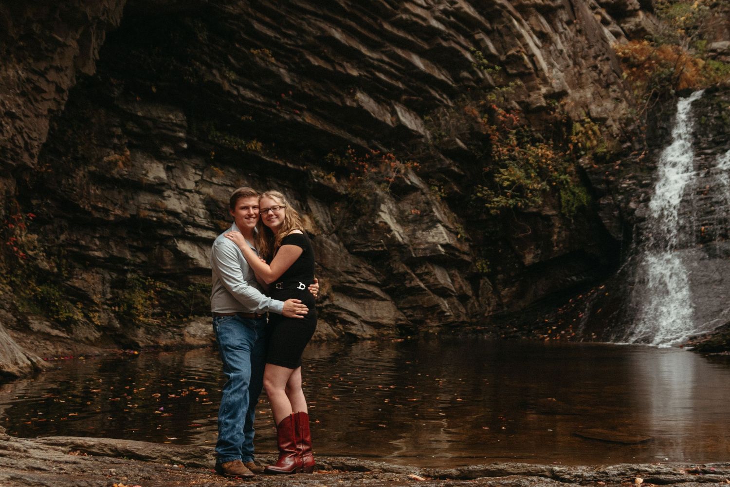 A dramatic waterfall cascades down dark rocky cliffs in a natural setting.