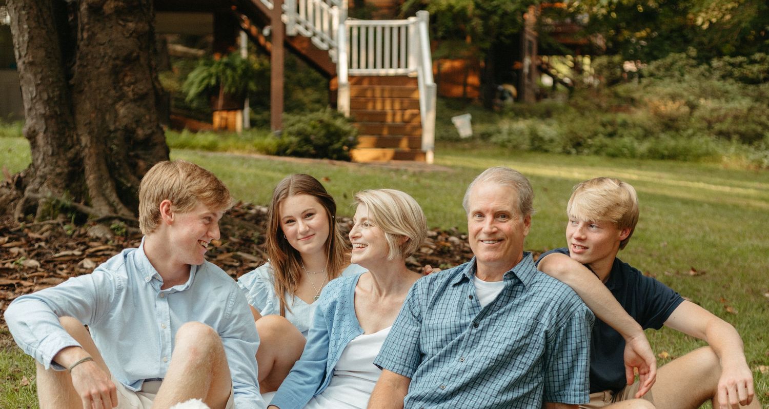 Family relaxes together outdoors on sunny autumn day.