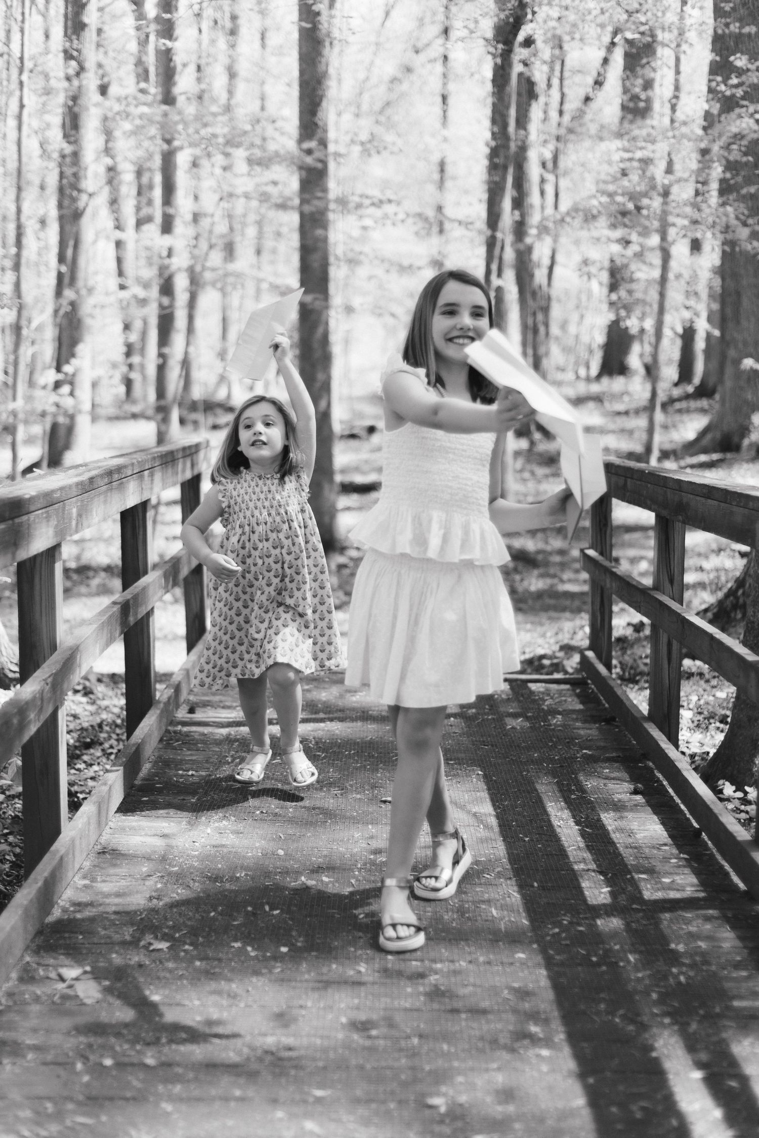 Black and white sequence of children playing on a wooden bridge in a forest setting.