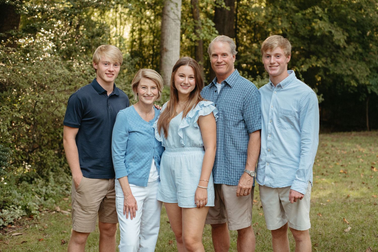 A group portrait of people in matching casual blue and khaki attire standing together on grass.