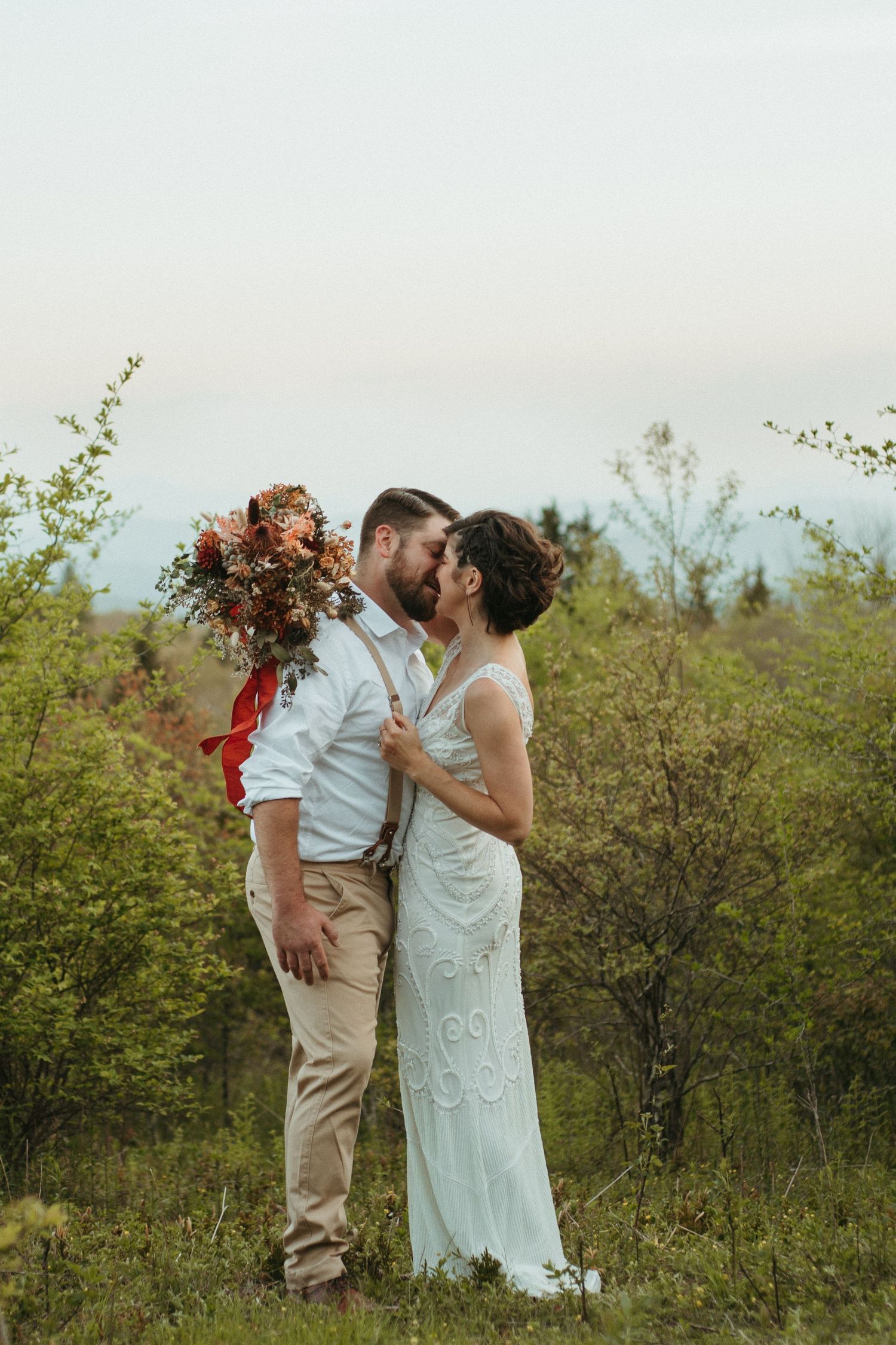 Couple sharing a romantic moment in a spring meadow with blooming shrubs.