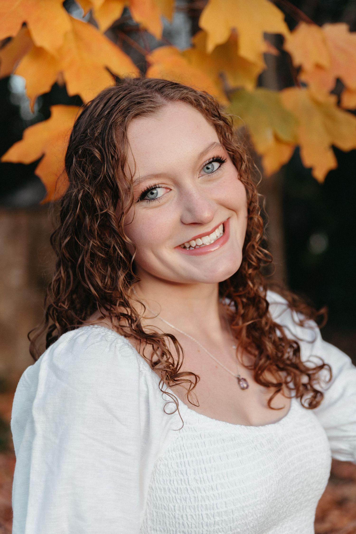 Autumn portrait series with orange maple leaves in background.