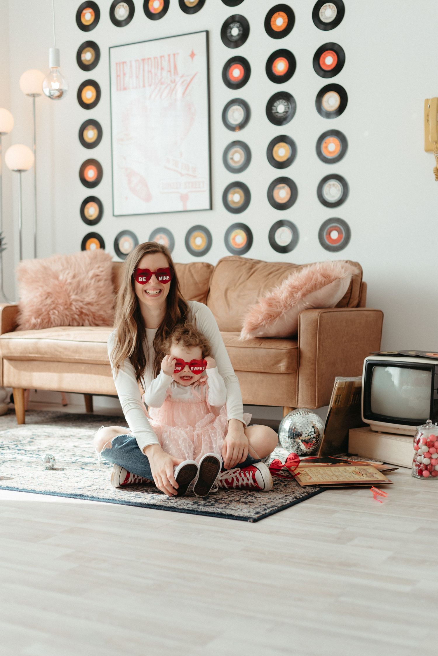 A series of four photos showing someone in a pink tulle skirt lounging on a brown couch with vintage records on the wall.