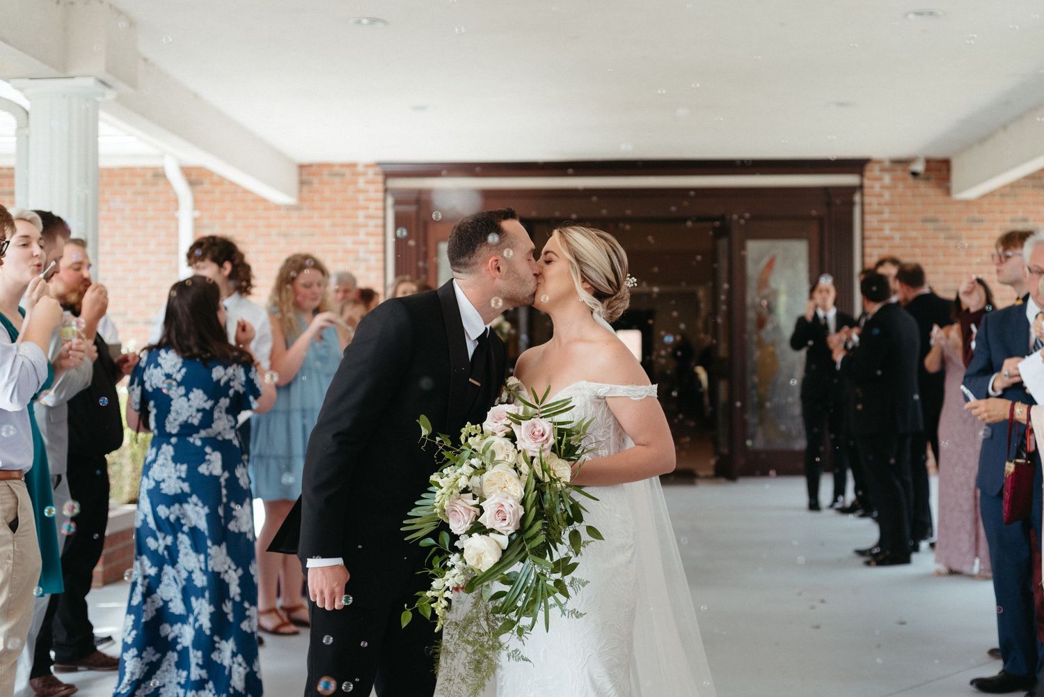 Large group gathering in an elegant indoor venue with exposed brick walls.