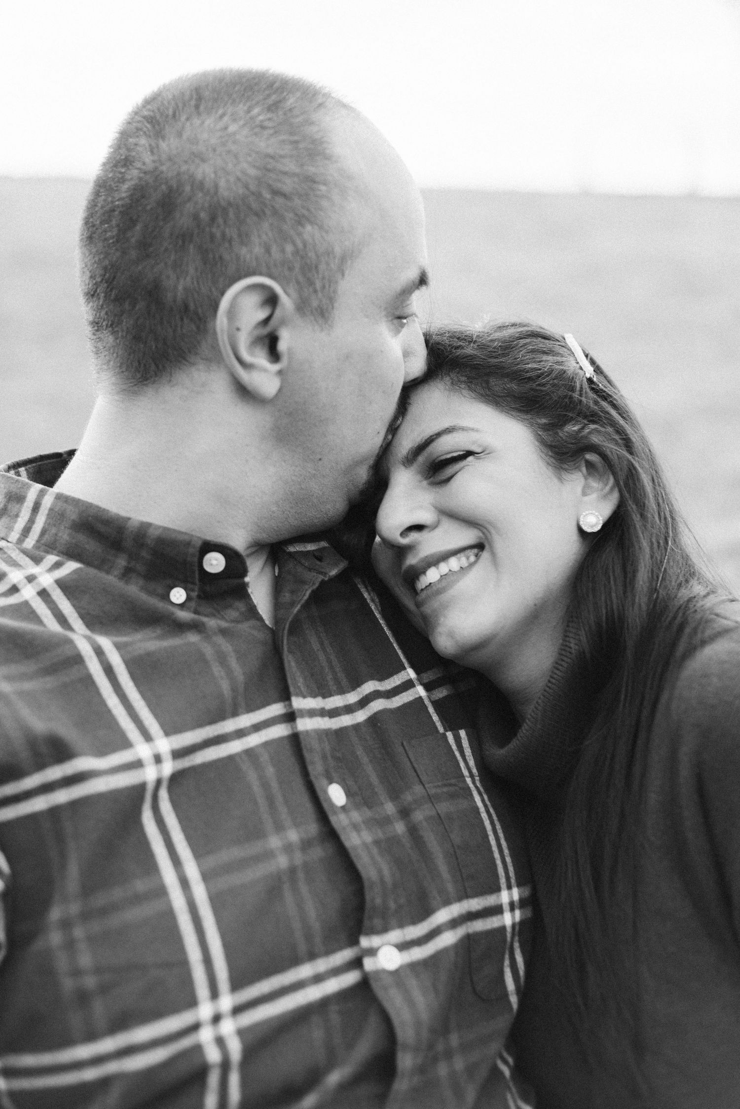 Intimate black and white portrait of couple in plaid sharing a tender moment.