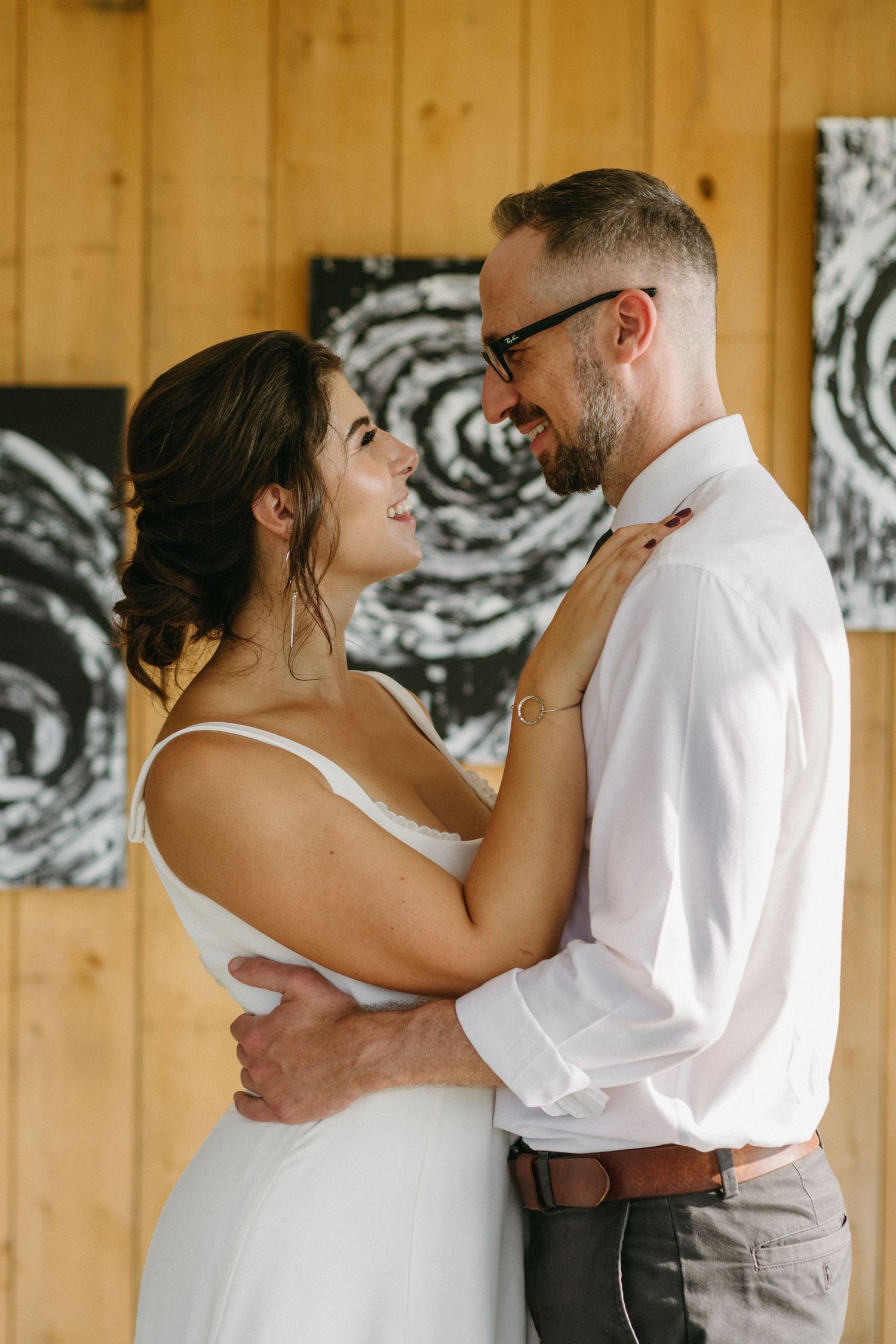 A couple shares an intimate moment in a rustic wooden room with artistic wall decorations.