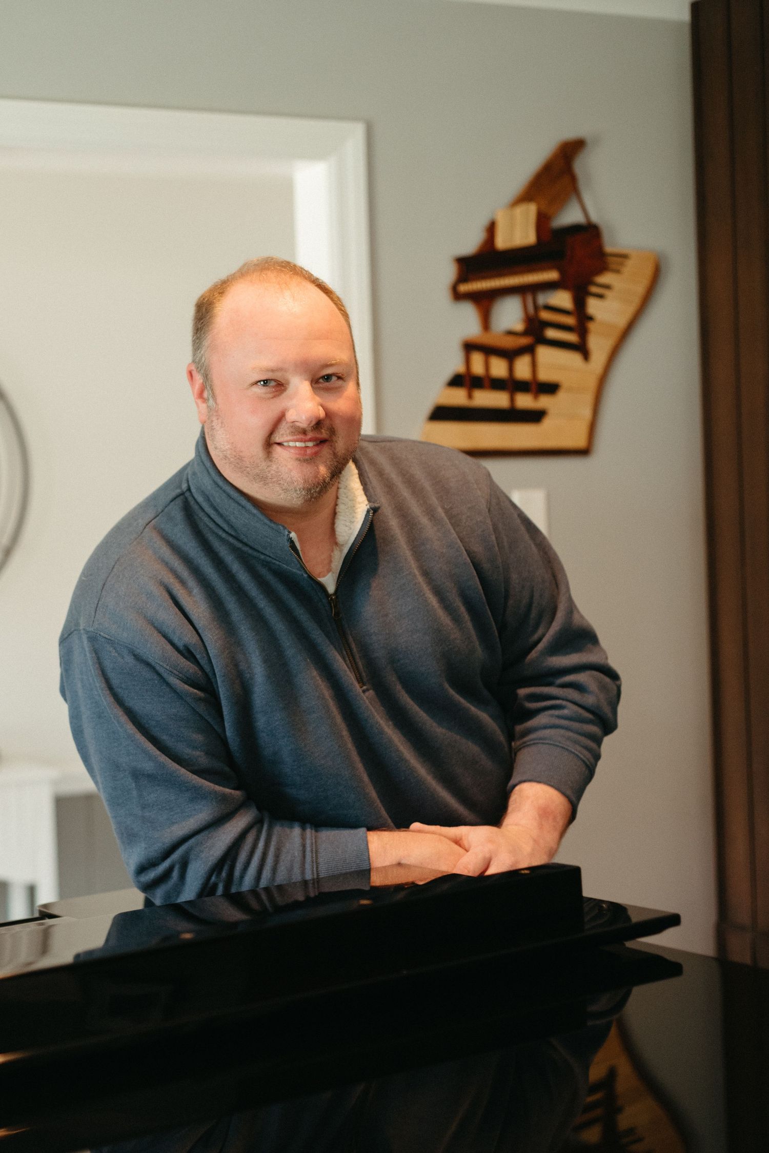 Portrait series at piano in grey sweater with natural lighting.