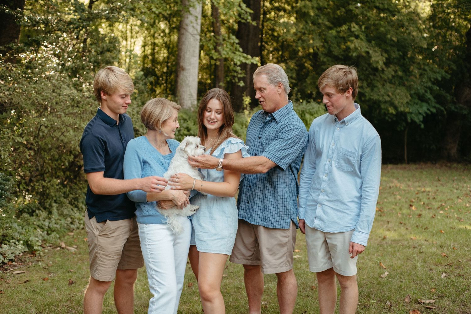 Family members in coordinated outfits stand together for a casual outdoor photo session.