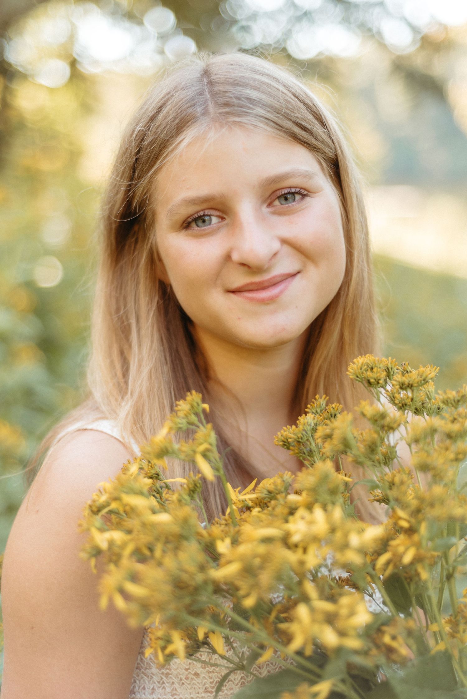 A portrait surrounded by yellow wildflowers with bokeh light effects in the background.