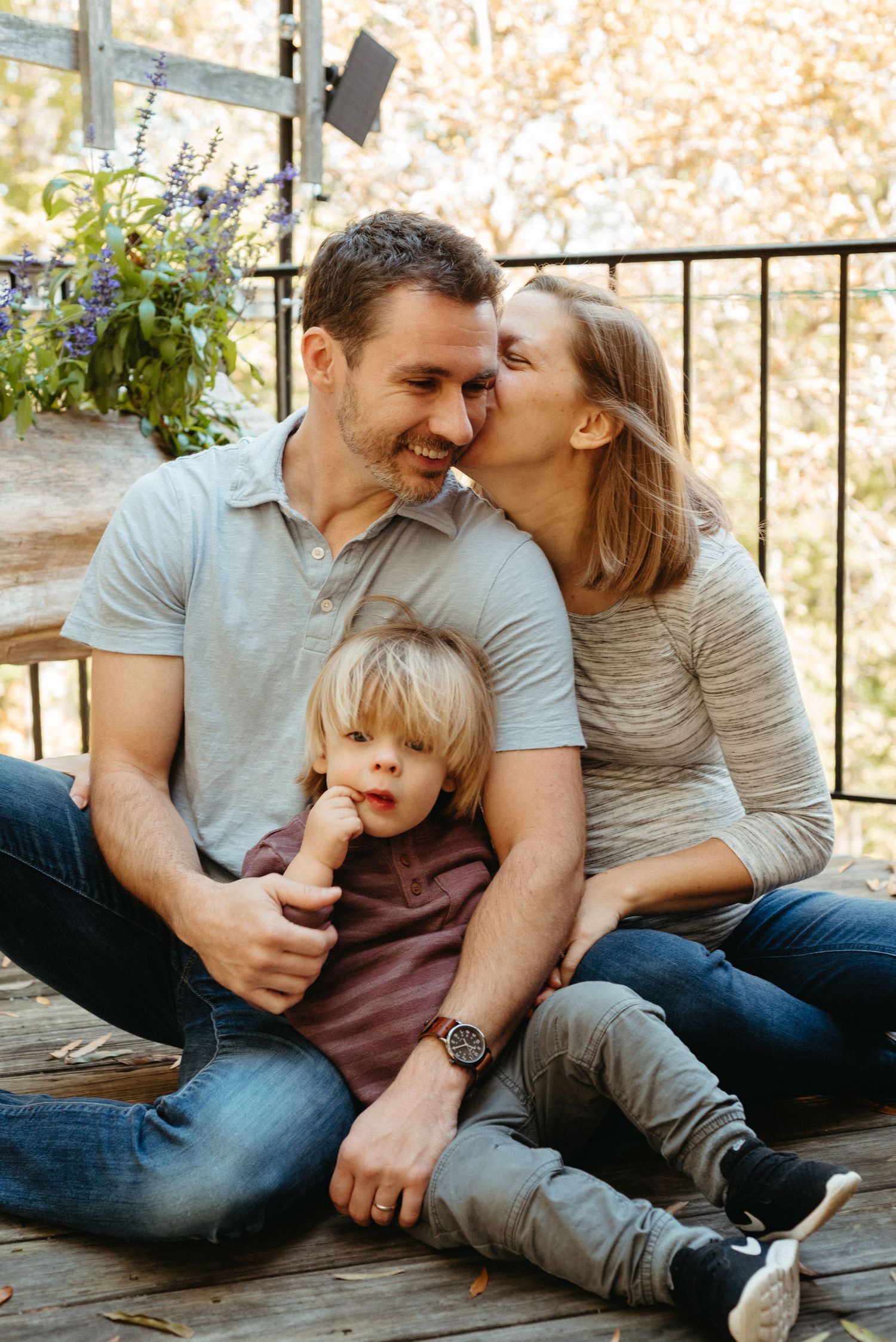 Family relaxing together on a wooden deck during an autumn afternoon.