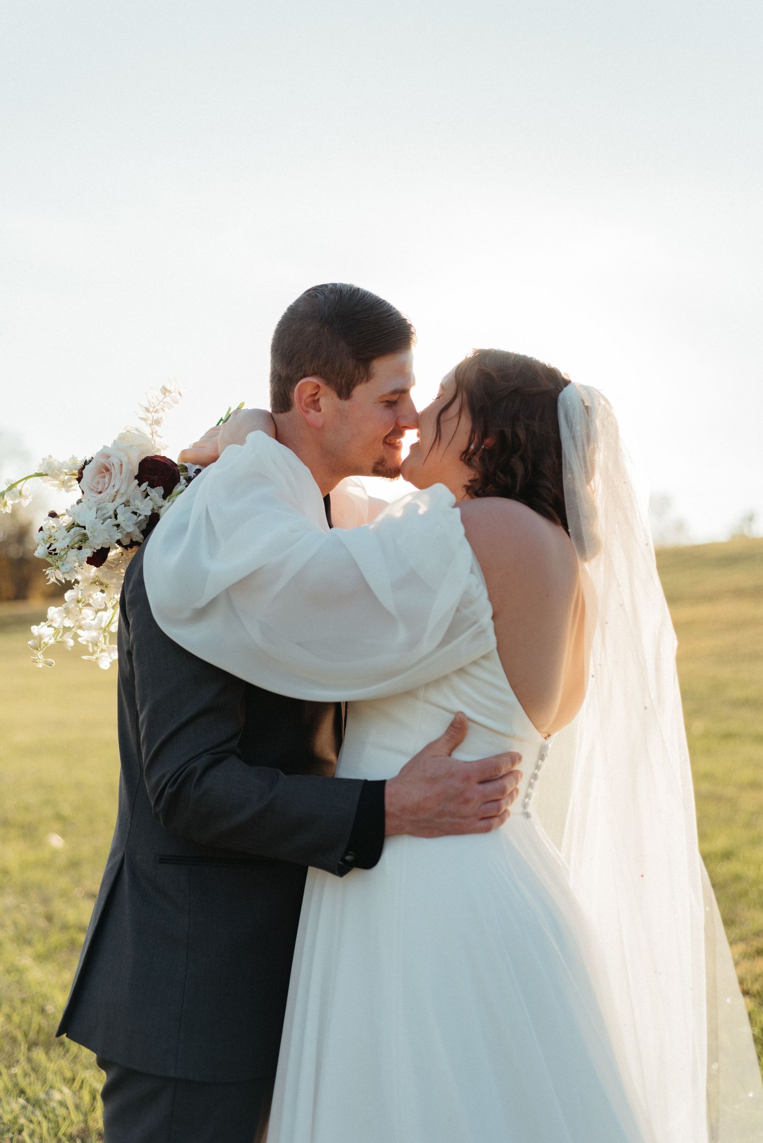 Intimate wedding couple portraits in a sunlit meadow during golden hour.