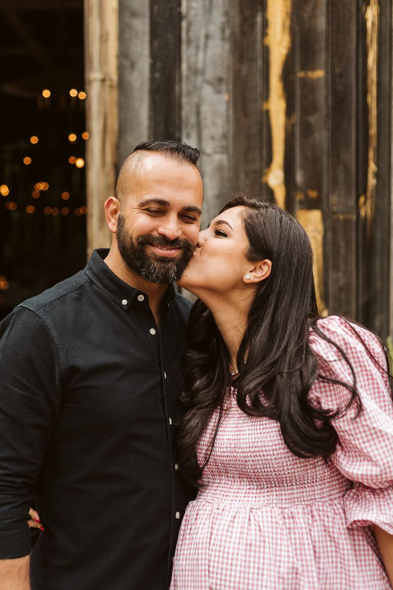 A couple shares tender moments in a series of romantic photos against a rustic wooden backdrop with twinkling lights.