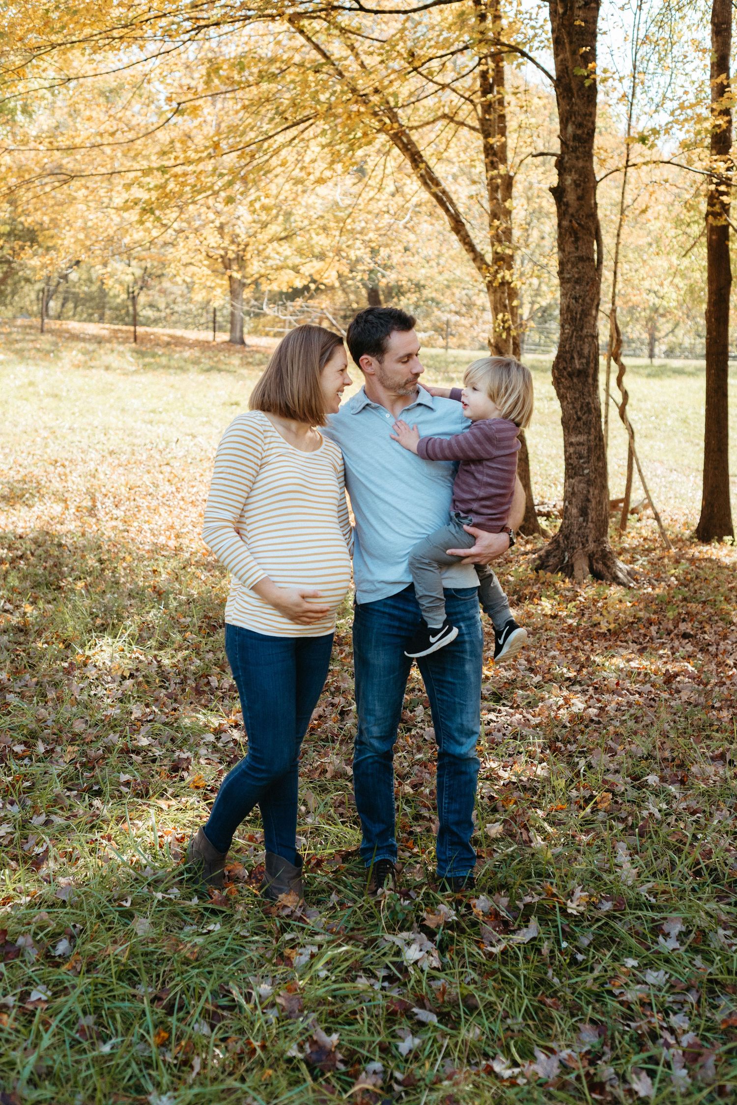 Family walking together through a forest with golden fall foliage.