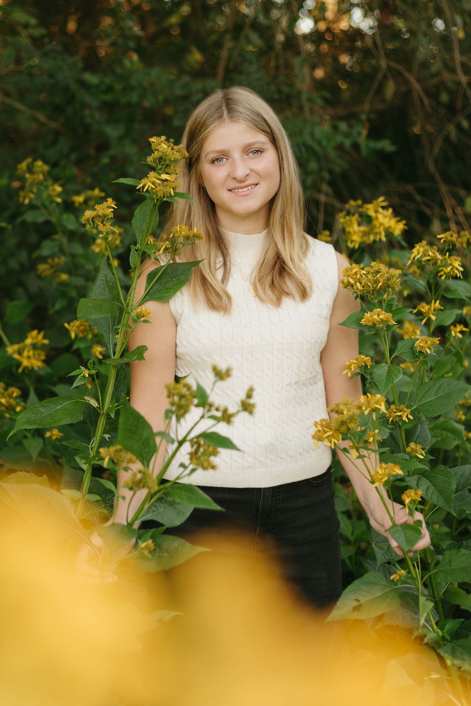 A portrait among blooming yellow wildflowers on a sunny day.