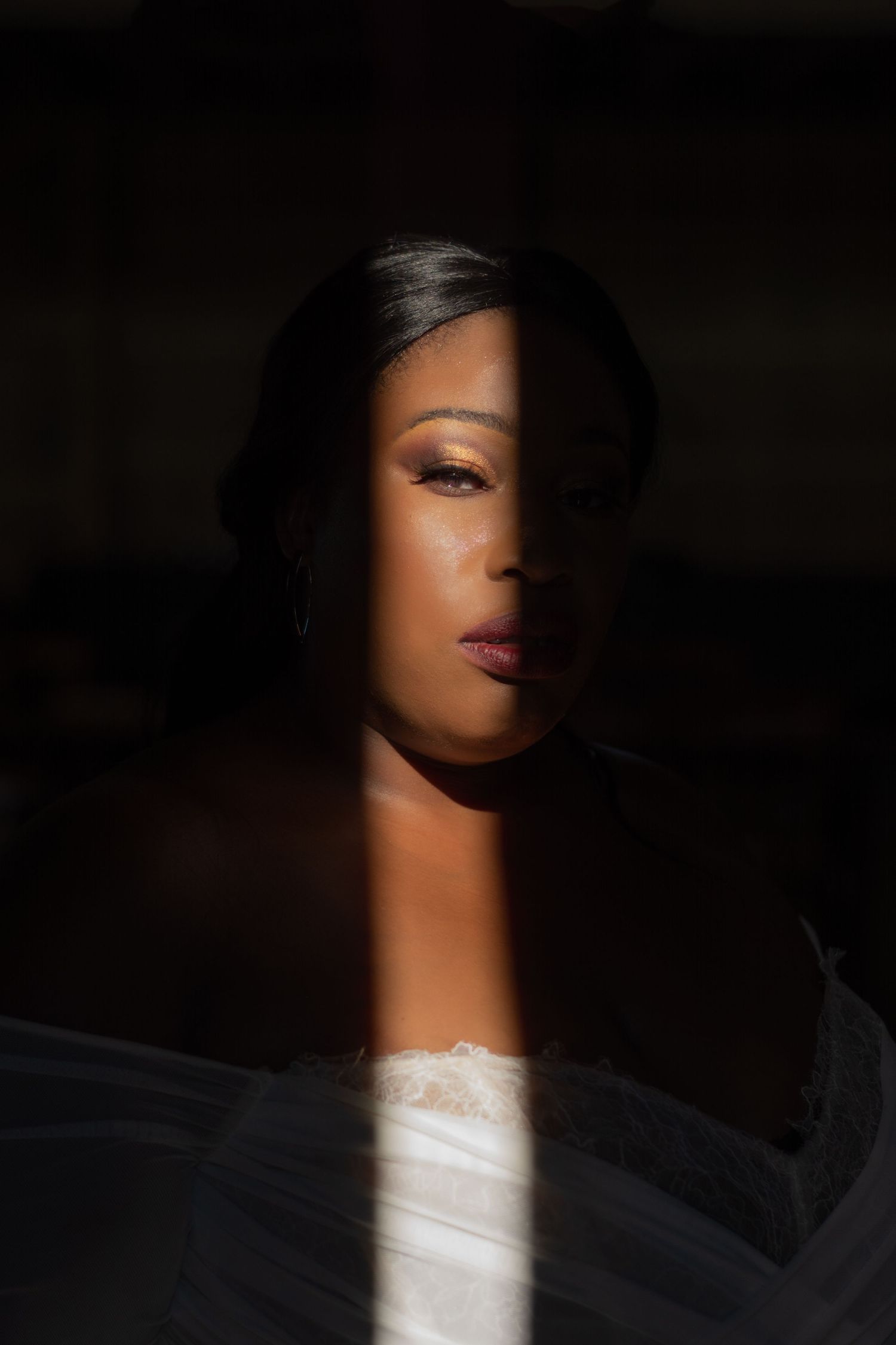 Dramatic side-lit portrait showing half a face in shadow with striking contrast.