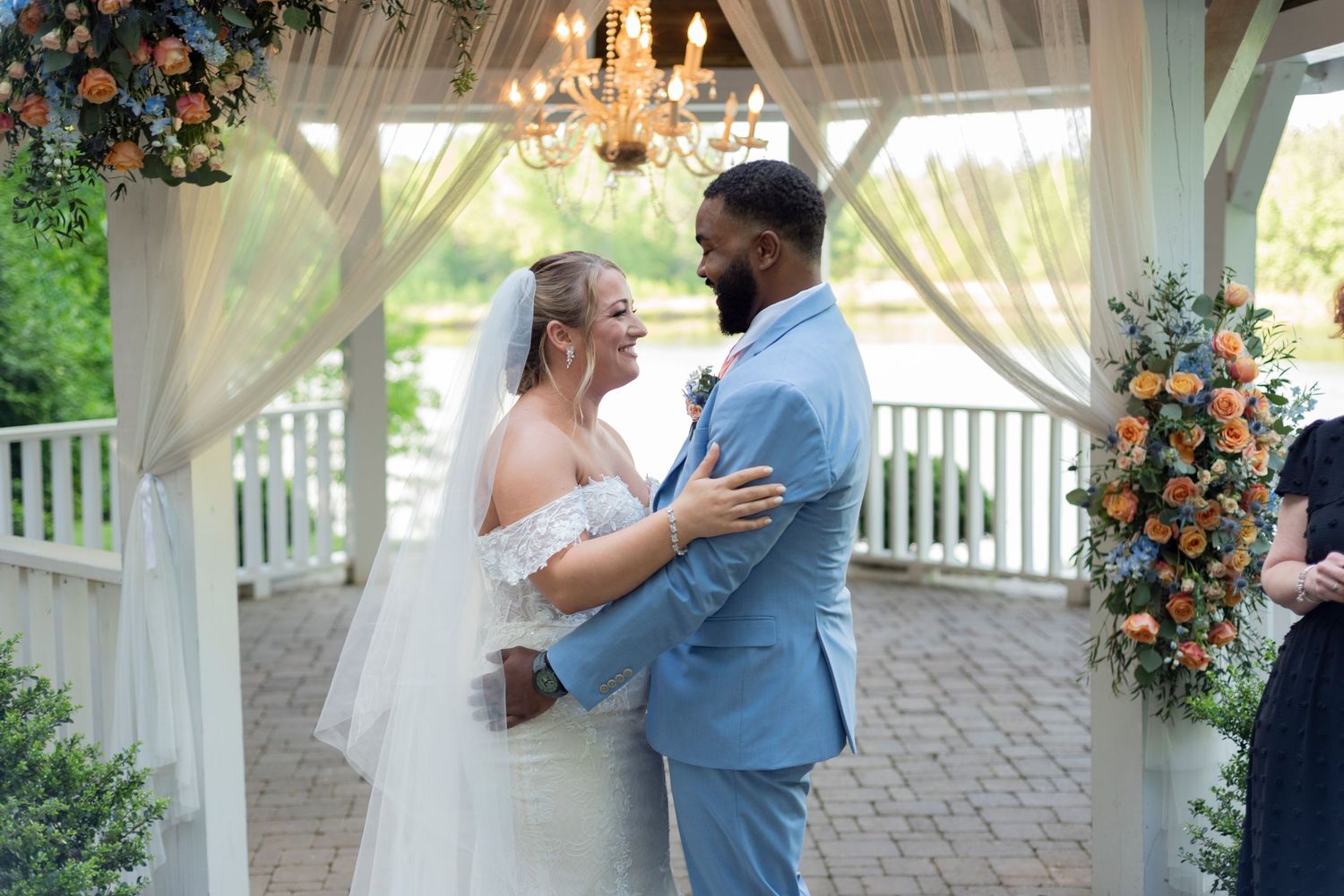 Wedding couple shares romantic moments under an elegant white gazebo with floral decorations.
