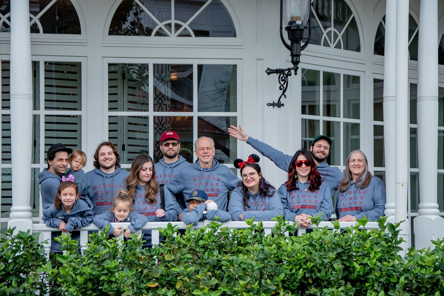 Large family group posing together on a porch wearing matching gray outfits and Disney ears at Walt Disney World.