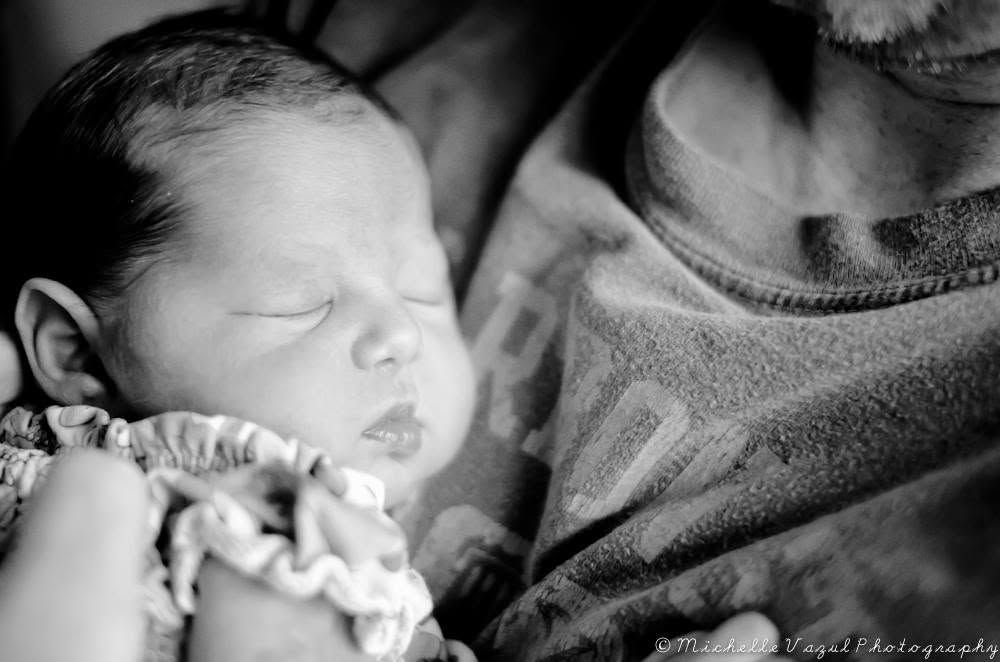 Black and white photo of a peaceful sleeping newborn baby wrapped in a soft blanket.
