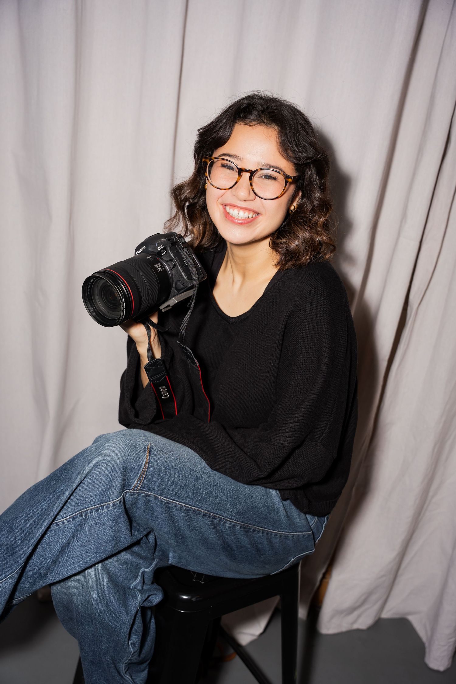 Portrait of woman holding large camera.