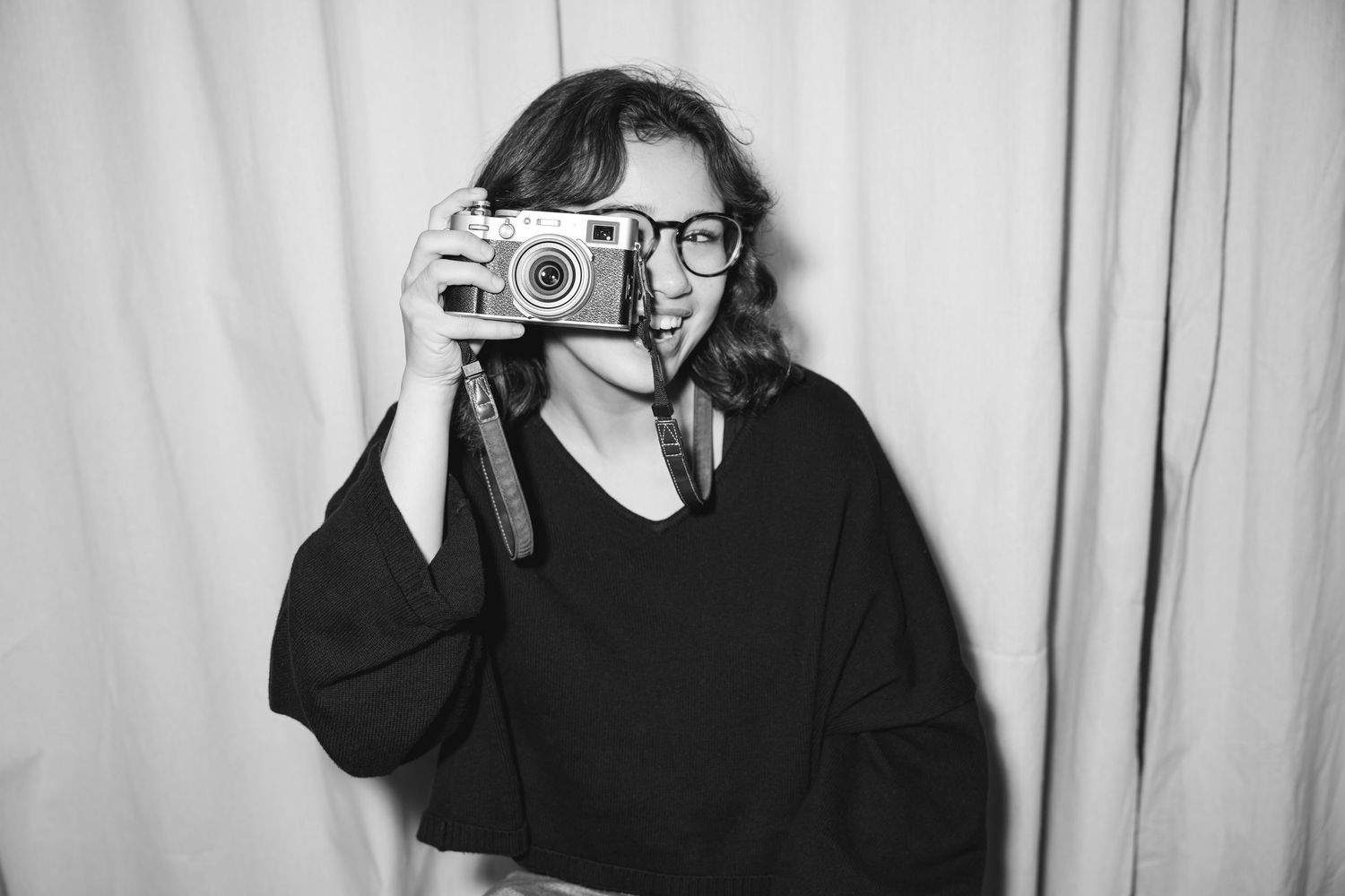 Black and white portrait of woman holding camera to eye.