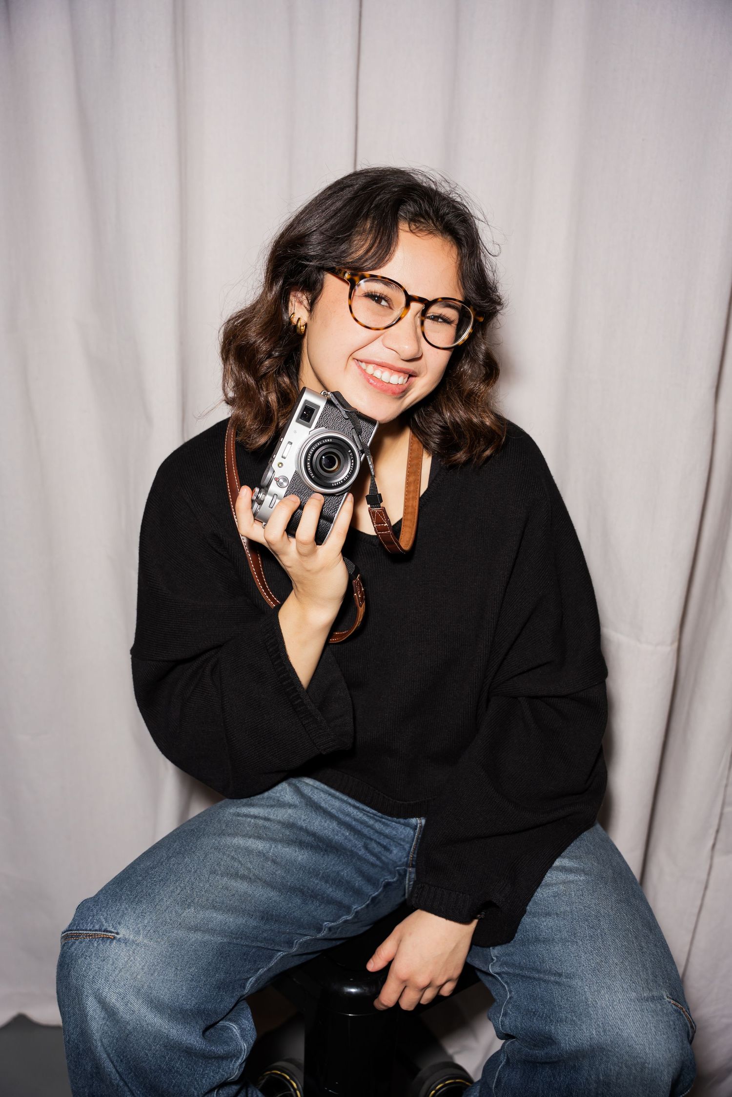 Portrait of woman holding camera under chin.