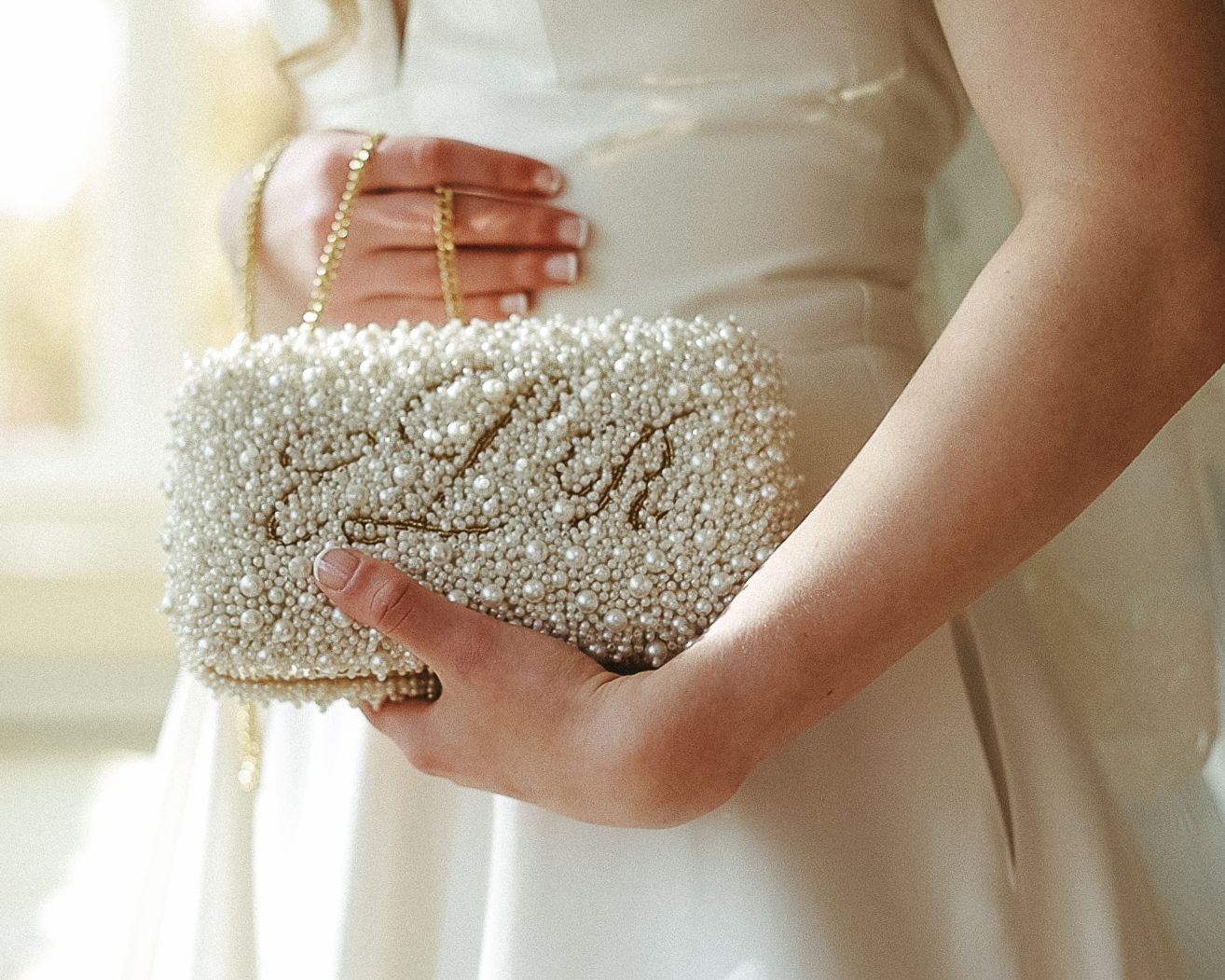 Close-up of a bride holding a pearl-encrusted custom clutch, a luxurious wedding day detail captured by a Scranton photographer.