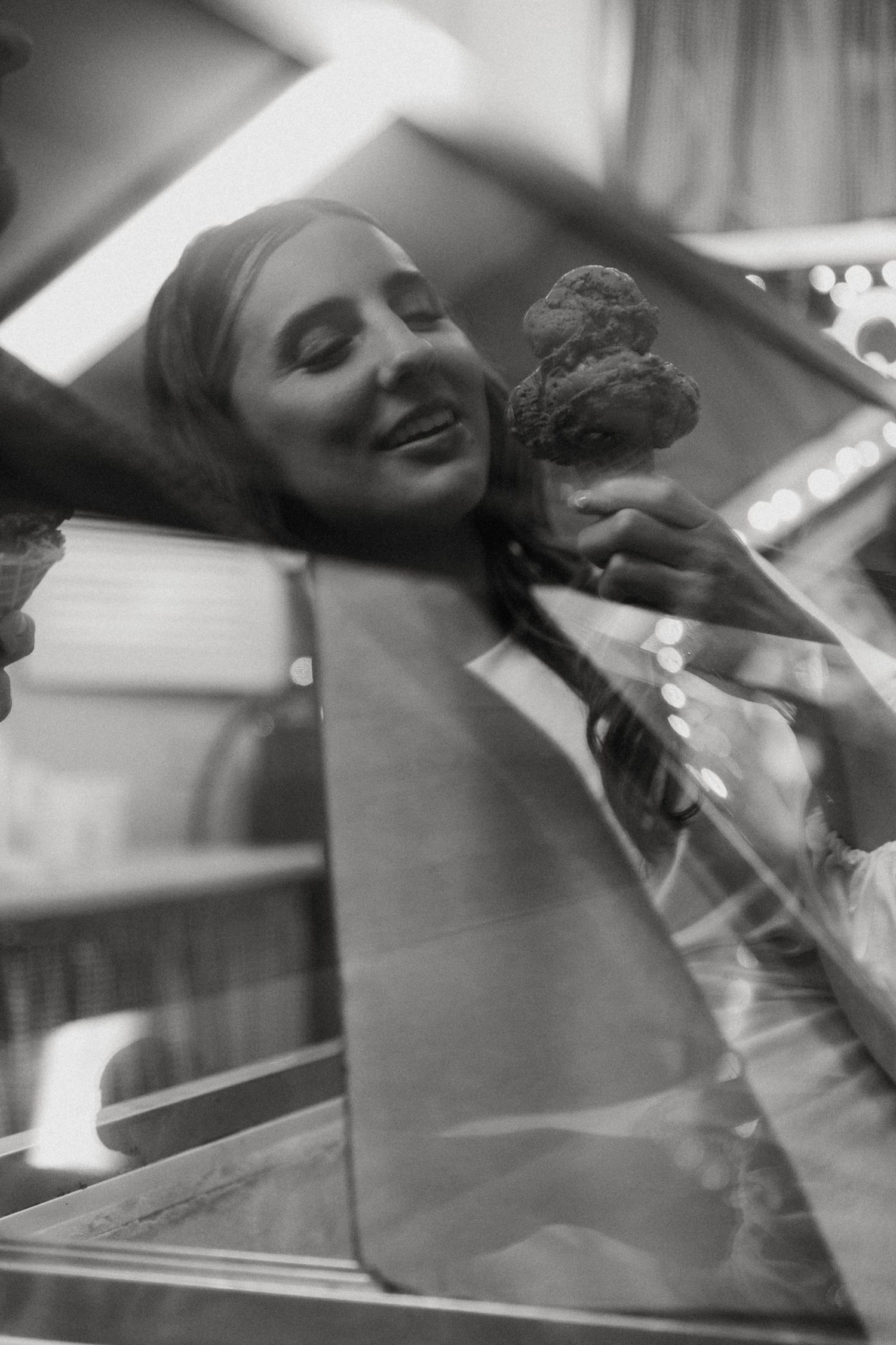 Black and white photo of smiling bride receiving ice cream cone through car window.