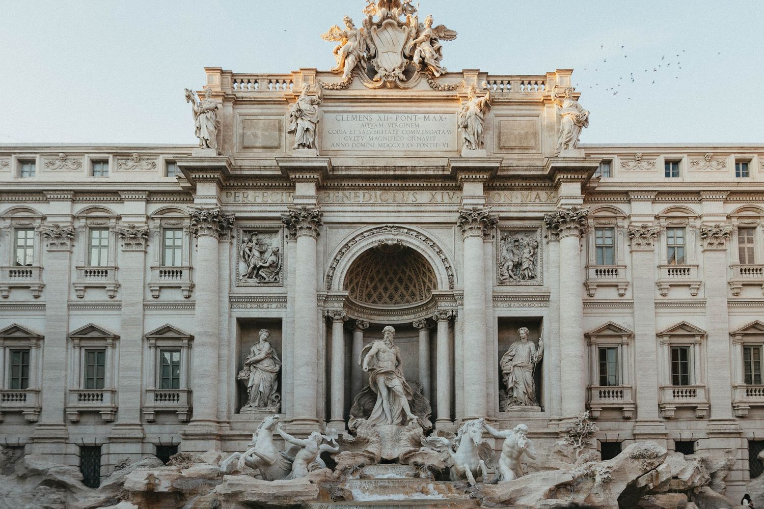 The iconic Trevi Fountain with elaborate Baroque sculptures in Rome, Italy at dusk.