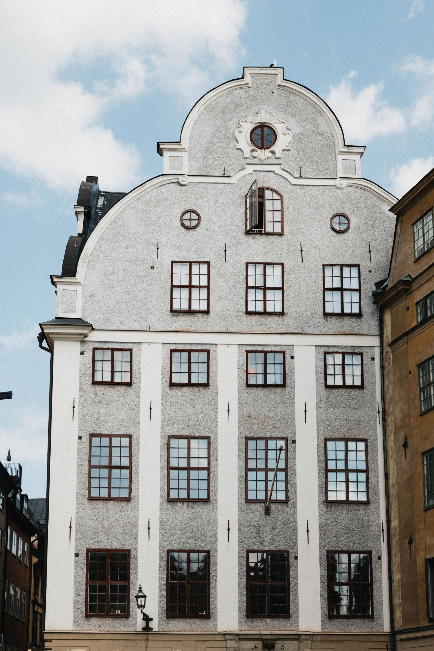 White Baroque-style building facade with arched gable and symmetrical windows in Stockholm.