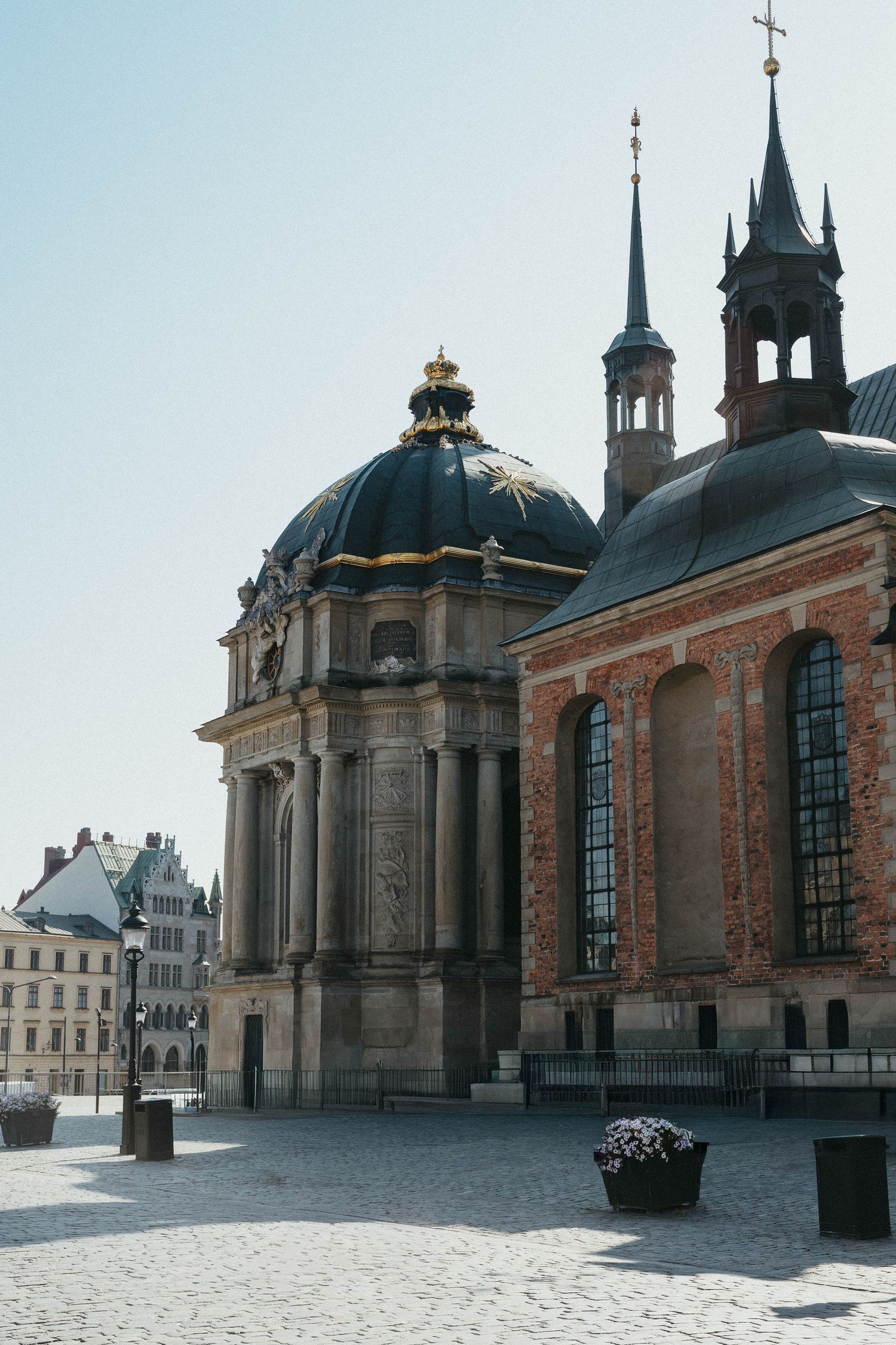 Baroque church dome with gold crown detail beside a brick cathedral in Stockholm.