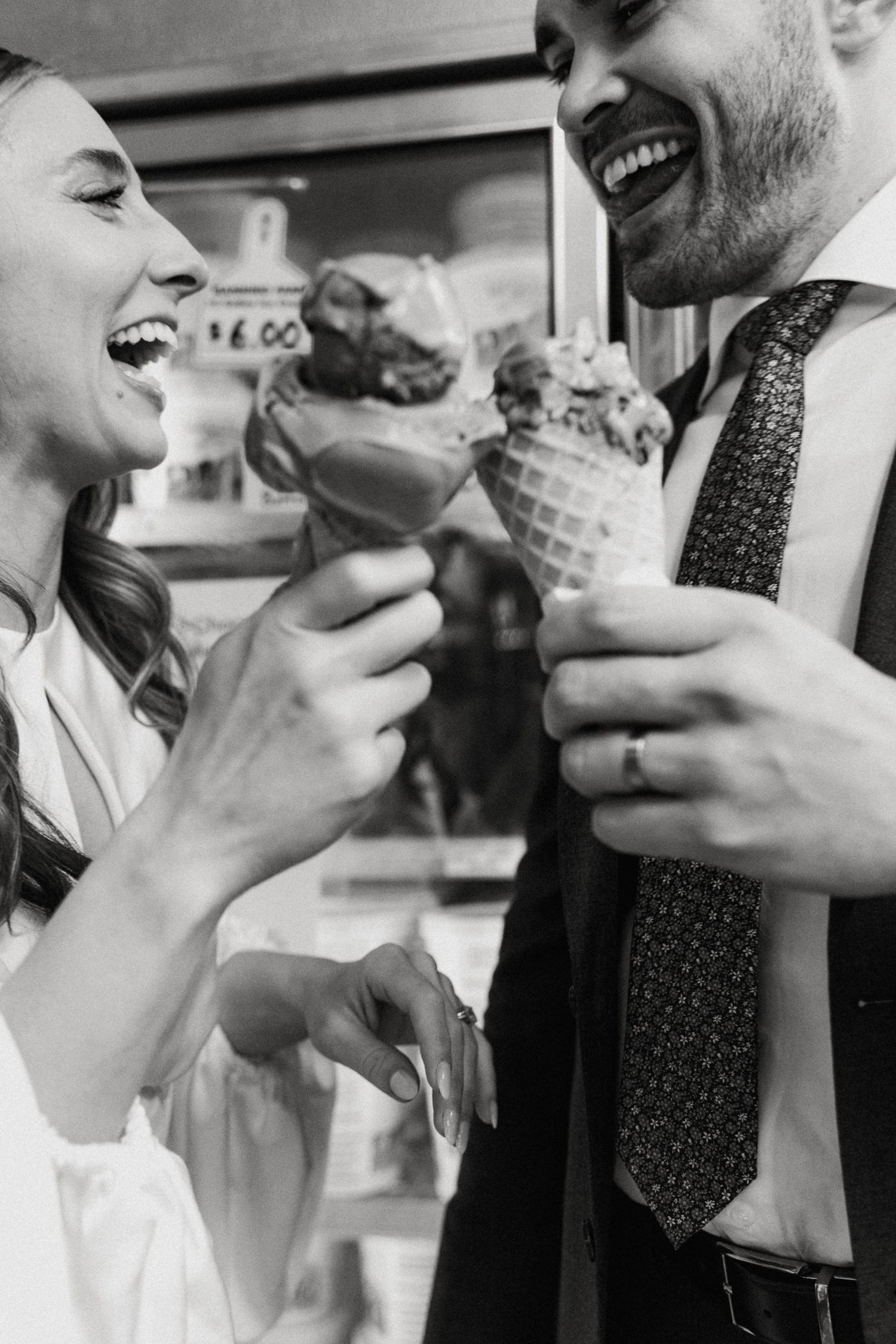Black and white photo of laughing bride and groom holding gelato ice cream cones.