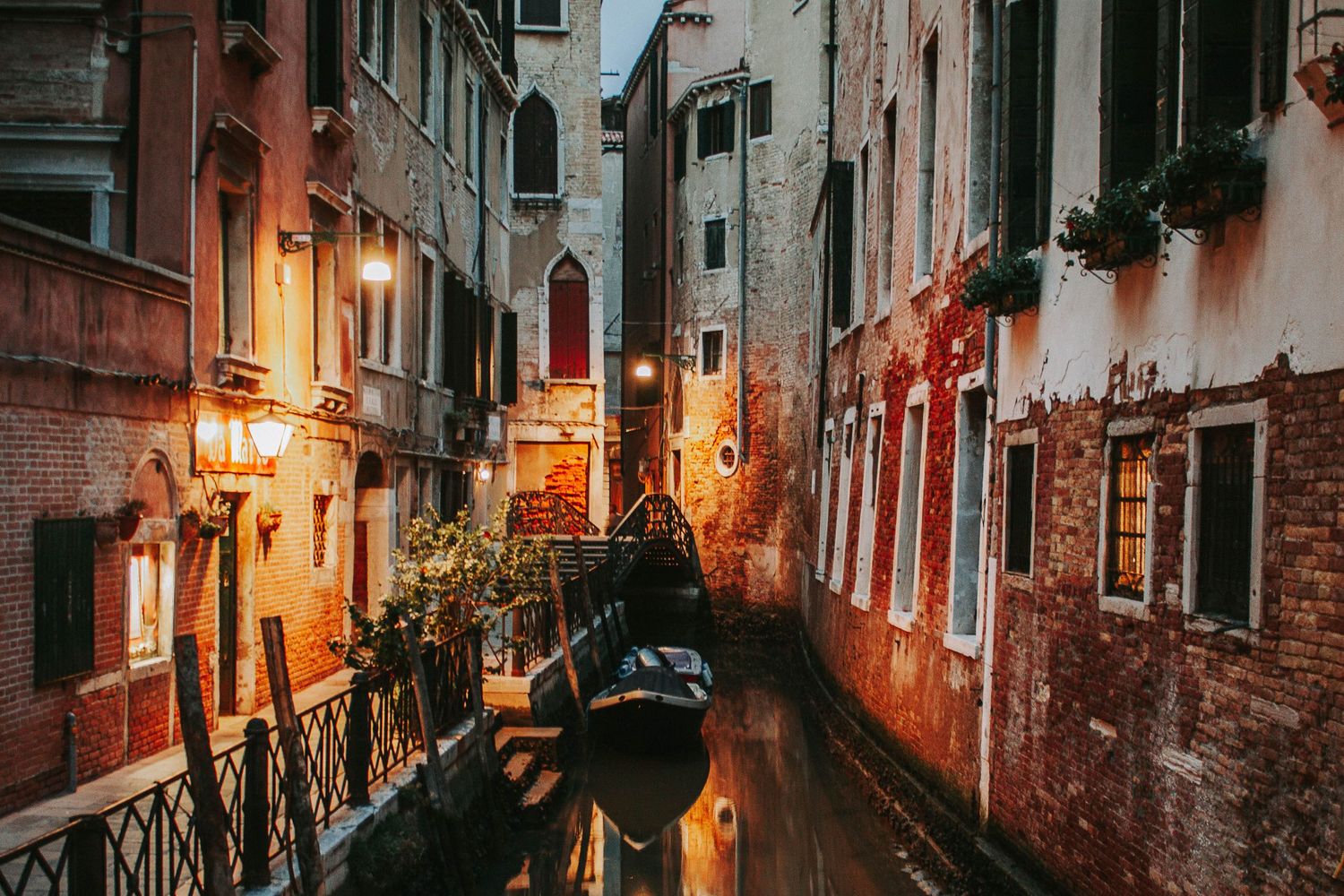 Romantic illuminated Venice canal at dusk with glowing lanterns reflecting on the water.