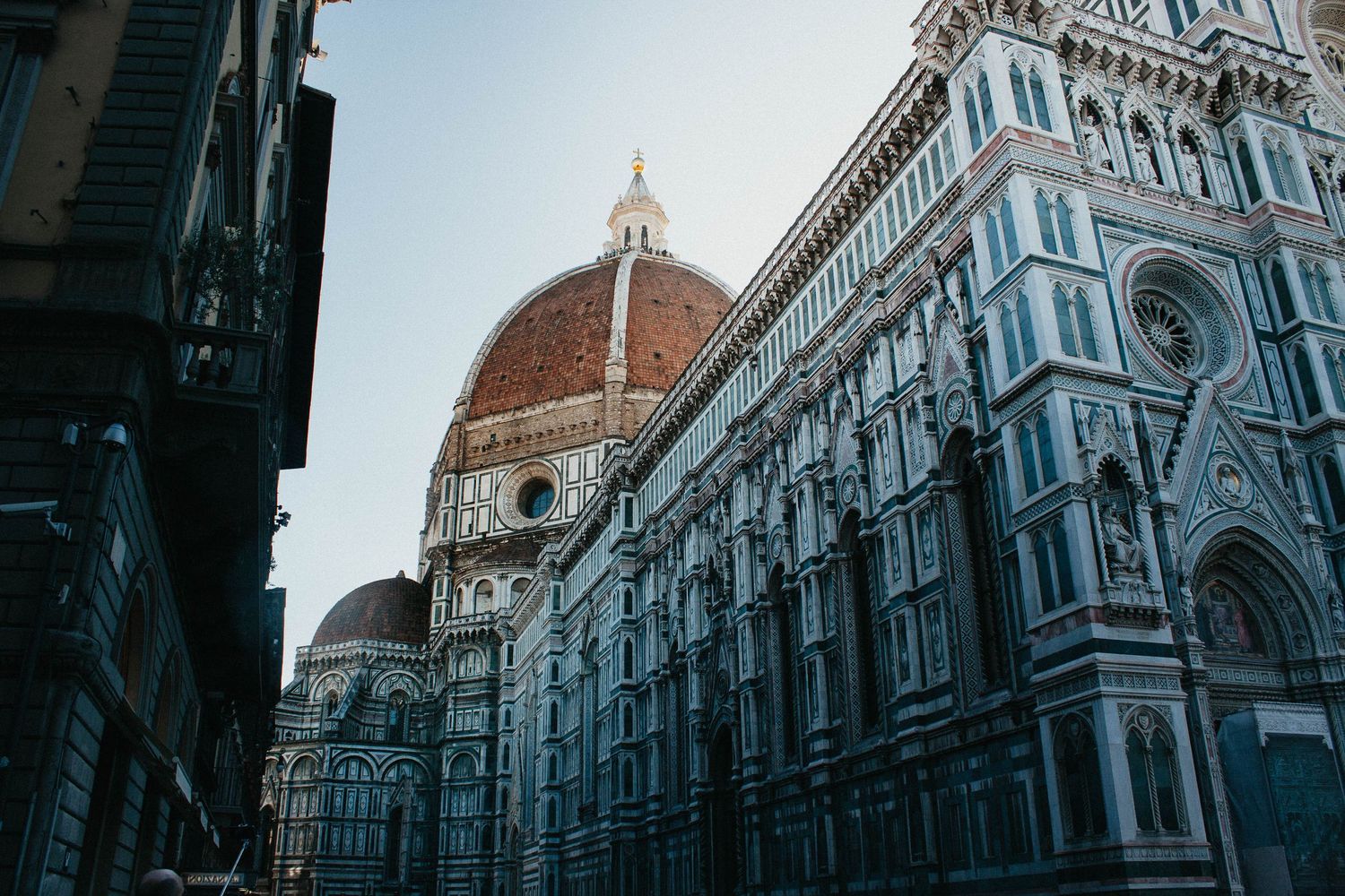 The iconic Florence Cathedral dome and ornate marble facade of the Duomo at dusk in Florence, Italy.