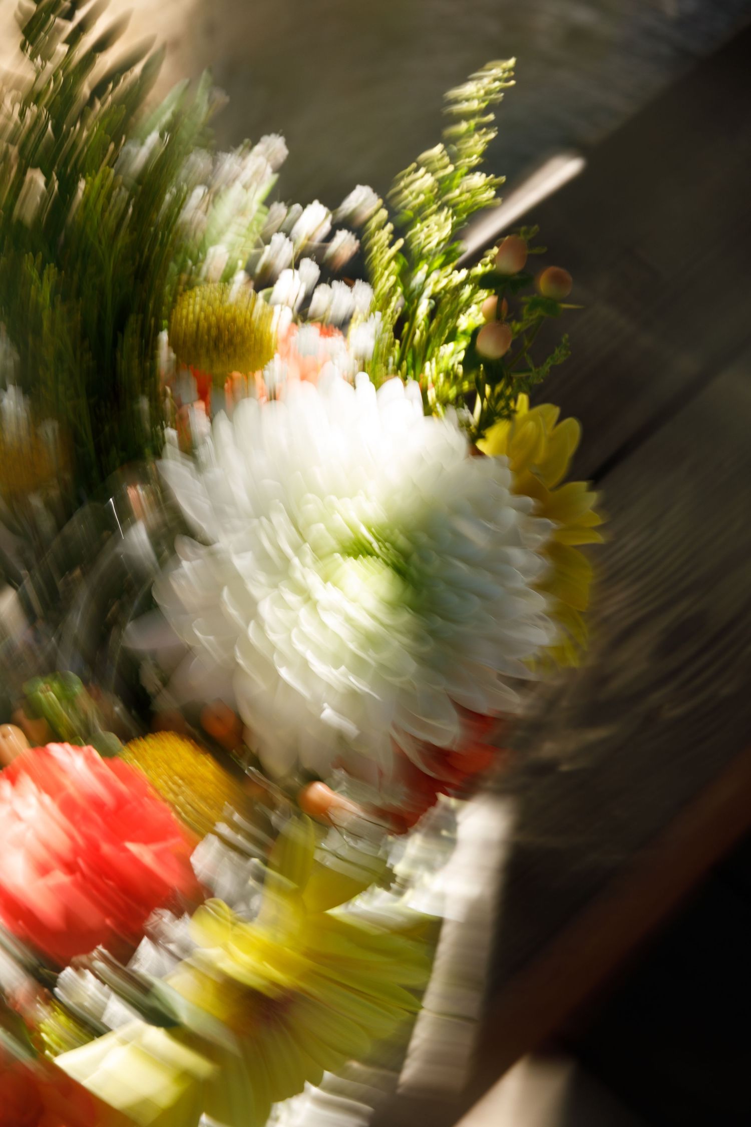 Blurred motion shot of colorful flower bouquet with white, red, and yellow blooms in soft focus.